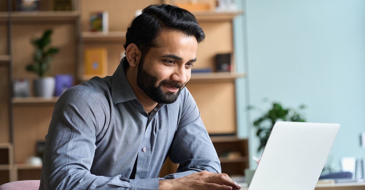 Man working on a laptop while smiling