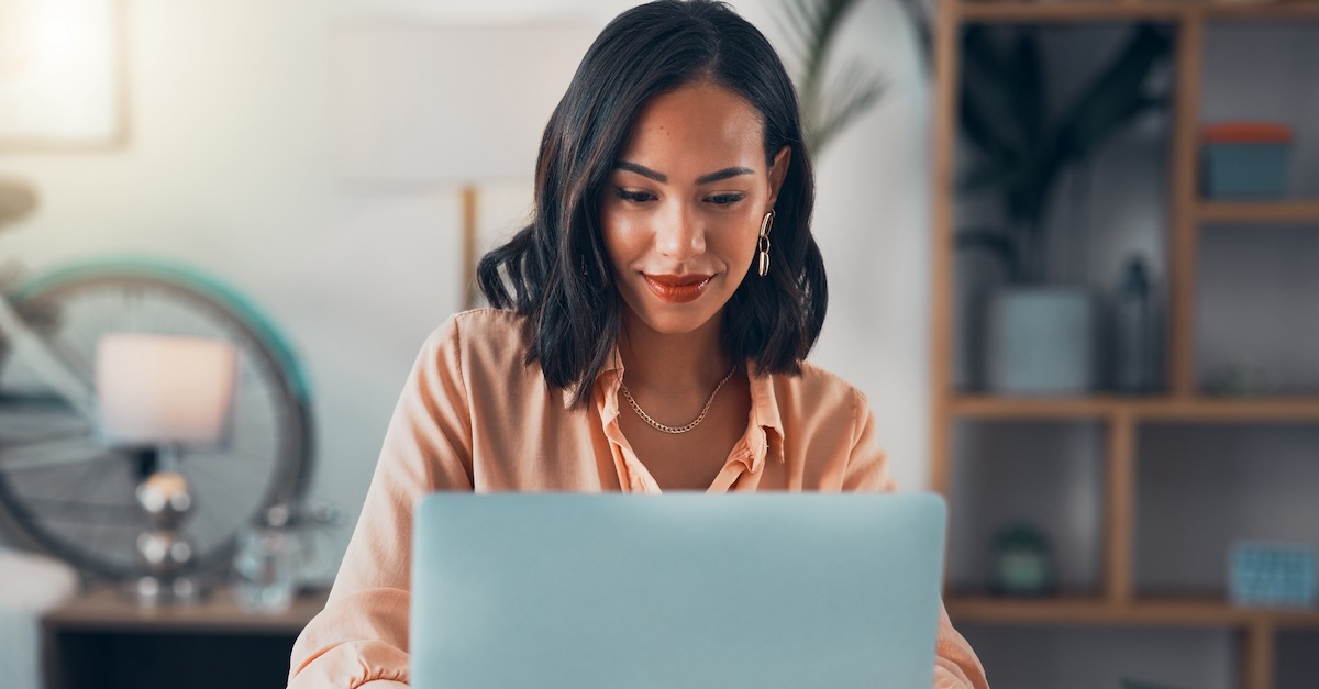 woman in a peach shirt typing her resume at home