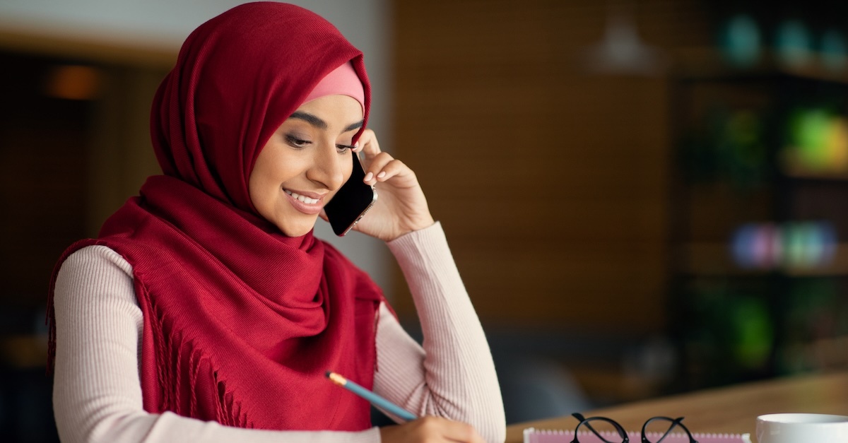Muslim woman wearing a red hijab on the phone