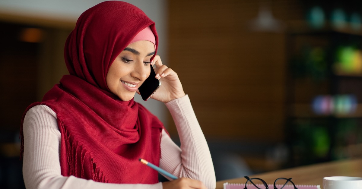 Muslim woman on phone wearing a red hijab