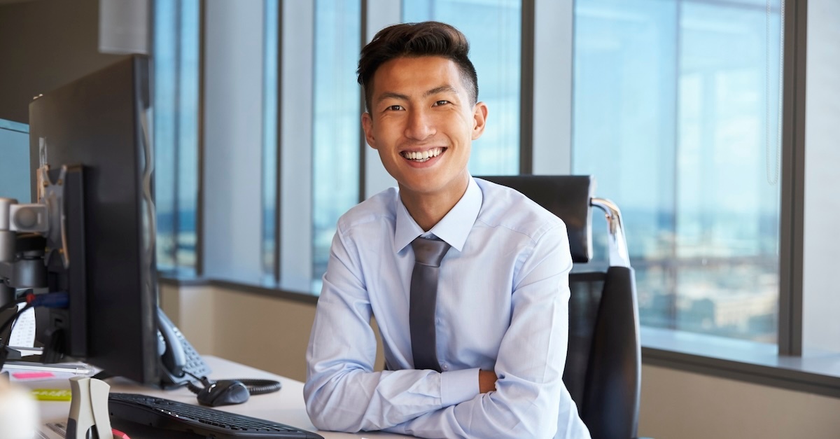 Man wearing a tie smiling at his desk in an office building