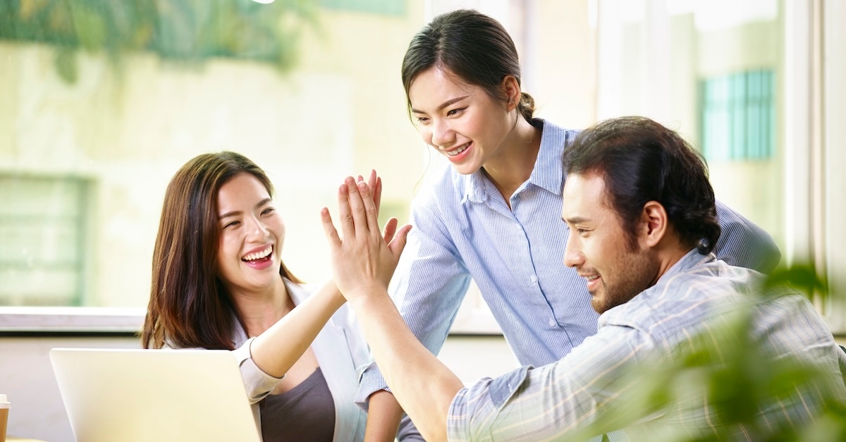 Three employees celebrating a work win with a high five