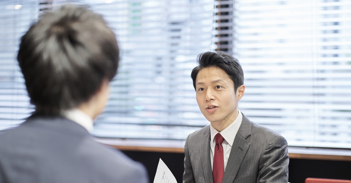 Man wearing business professional suit interviewing a potential employee with a resume in hand