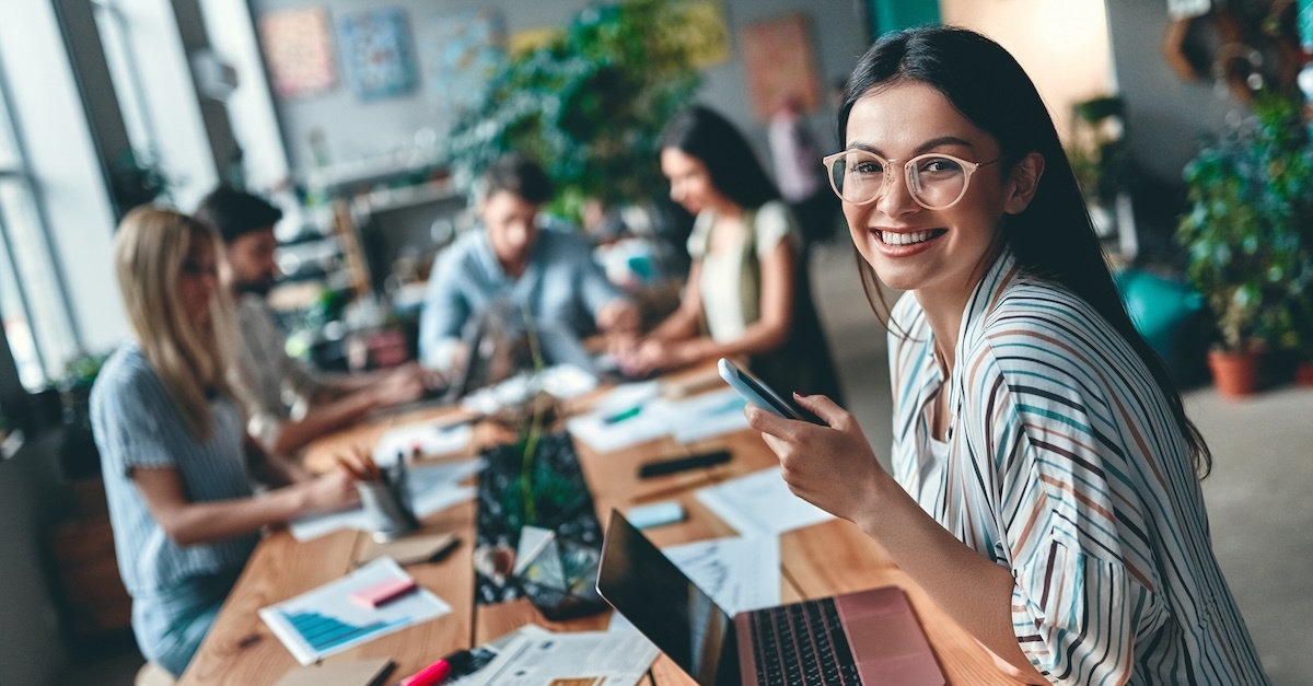 woman at work table with employees behind her