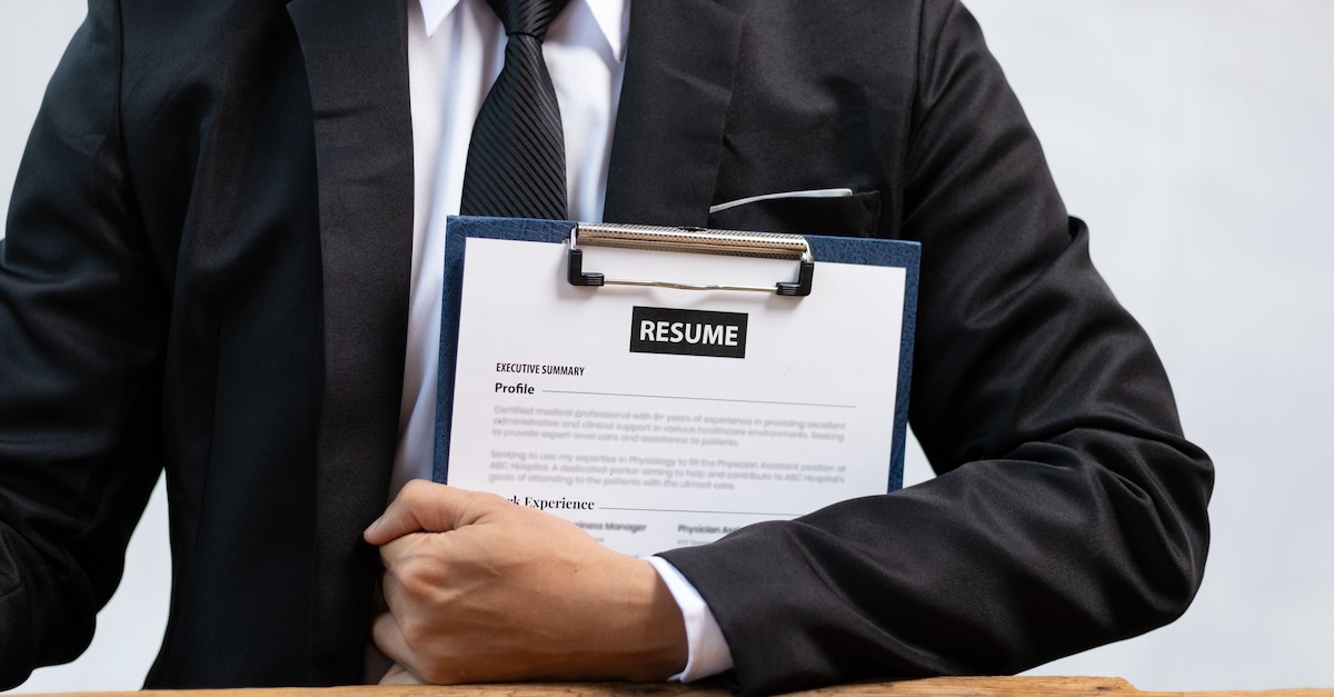 Man wearing a suit and tie holding his resume