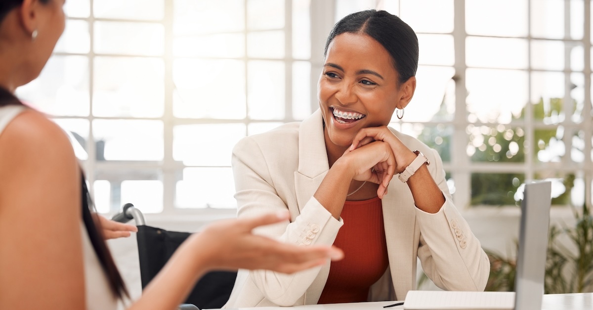 woman in tan blazer talking with another woman