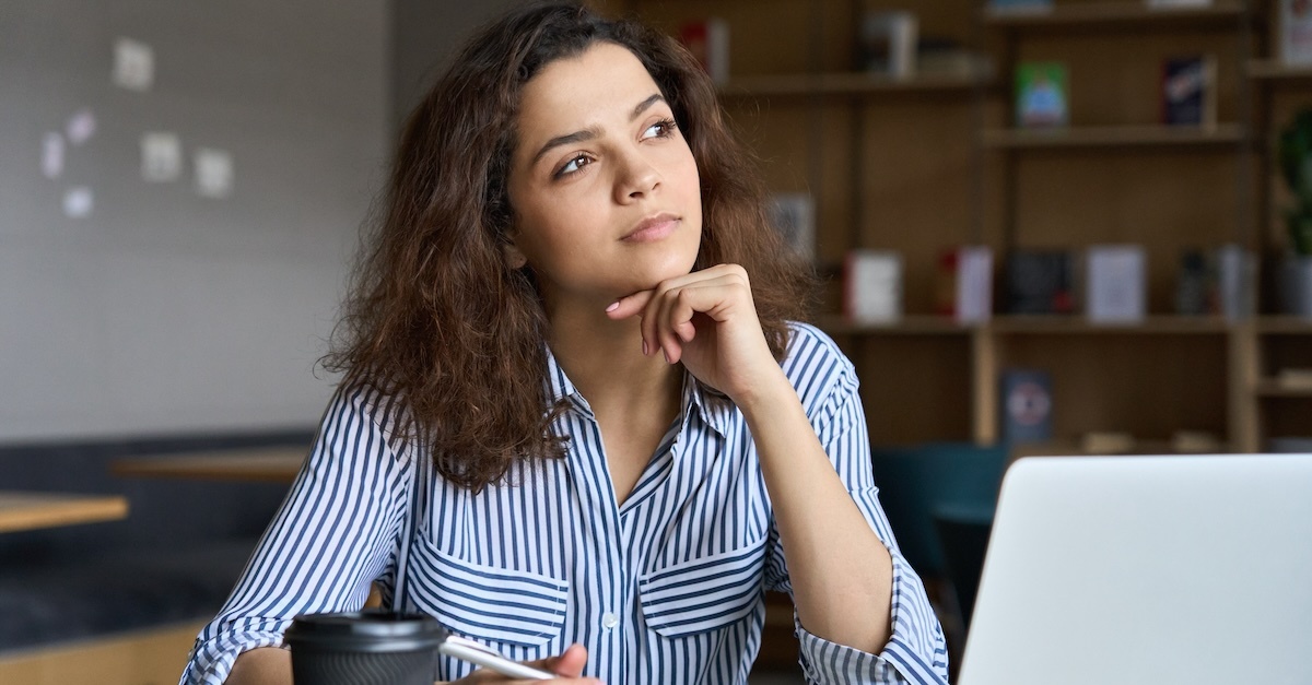 Woman writing a resignation letter with a coffee and her laptop