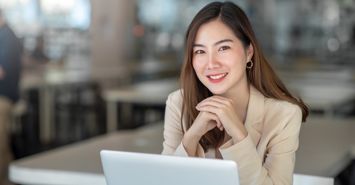 Woman at office and smiling in front of a laptop