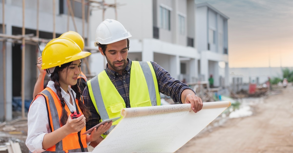 a group of three people at a construction site looking at plans