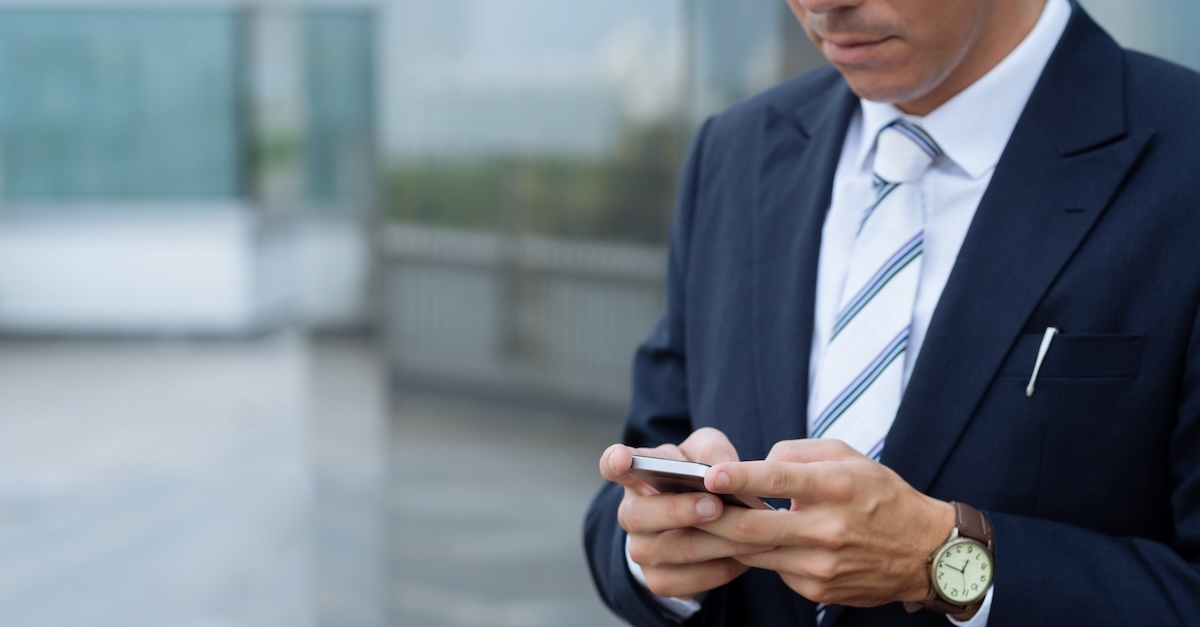 a close-up shot of a man in business attire holding a cell phone
