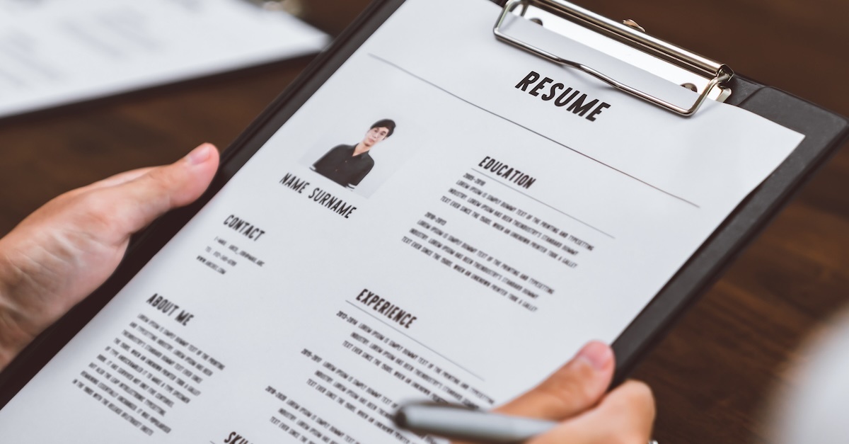 Resume on a clipboard with a person holding it reviewing