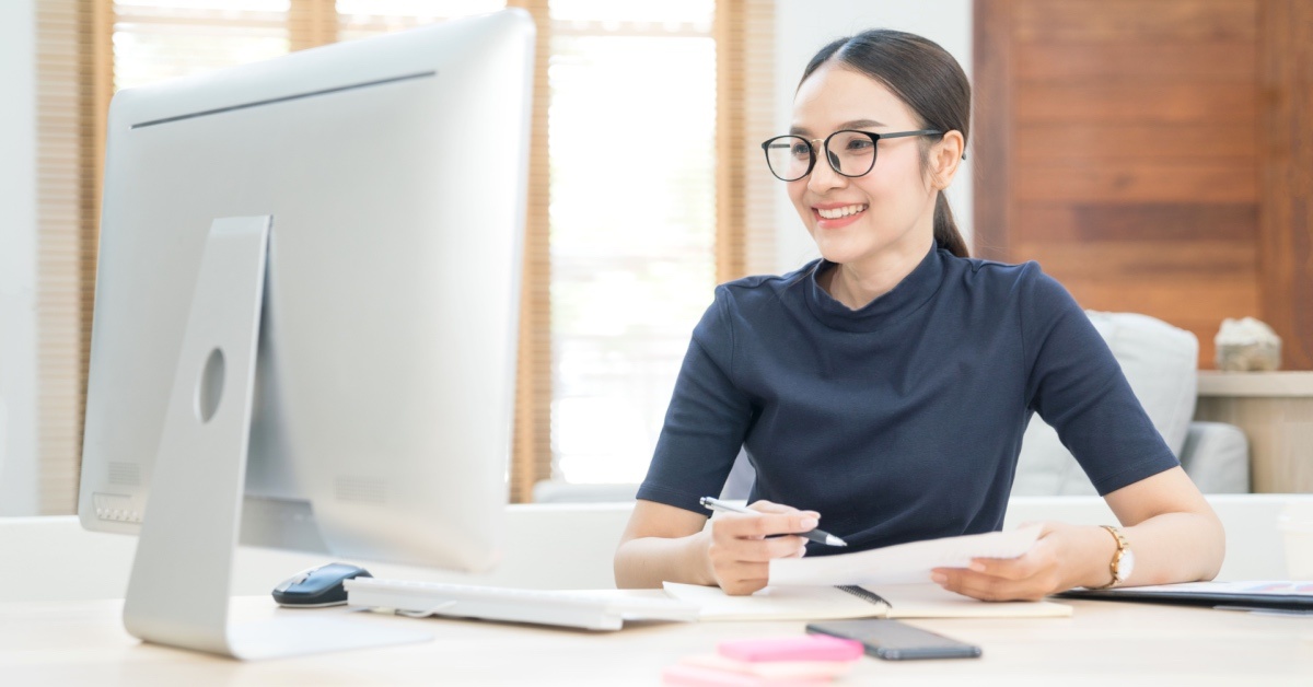 Asian woman sitting in front of a computer smiling