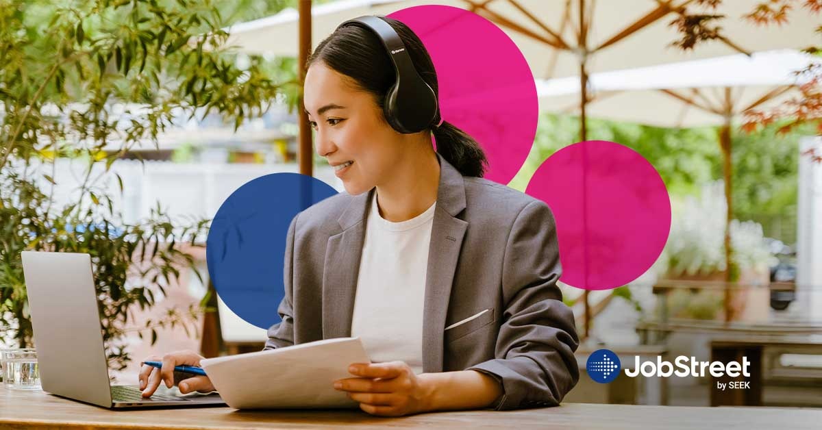 A woman writing her personal resignation at a cafe outside while wearing headphones