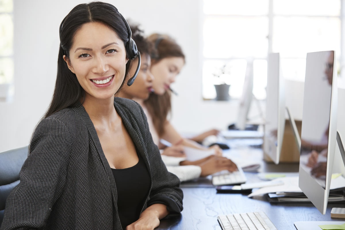 Seorang telemarketer wanita tampak bahagia ketika bekerja.