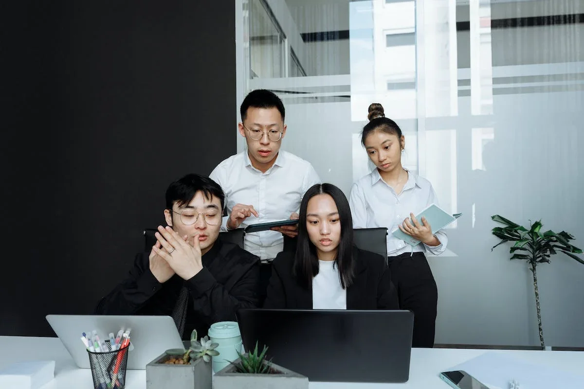 Empat orang karyawan sedang mengukur performa marketing melalui Google Data Studio atau Google Looker Studio di laptop.