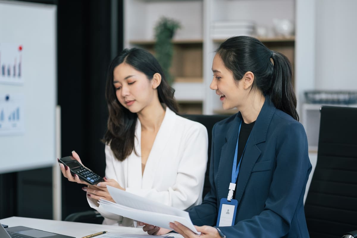 Dua orang karyawan wanita sedang berdikusi dan menghitung besaran pajak natura di kantor. (Sumber: Envato)