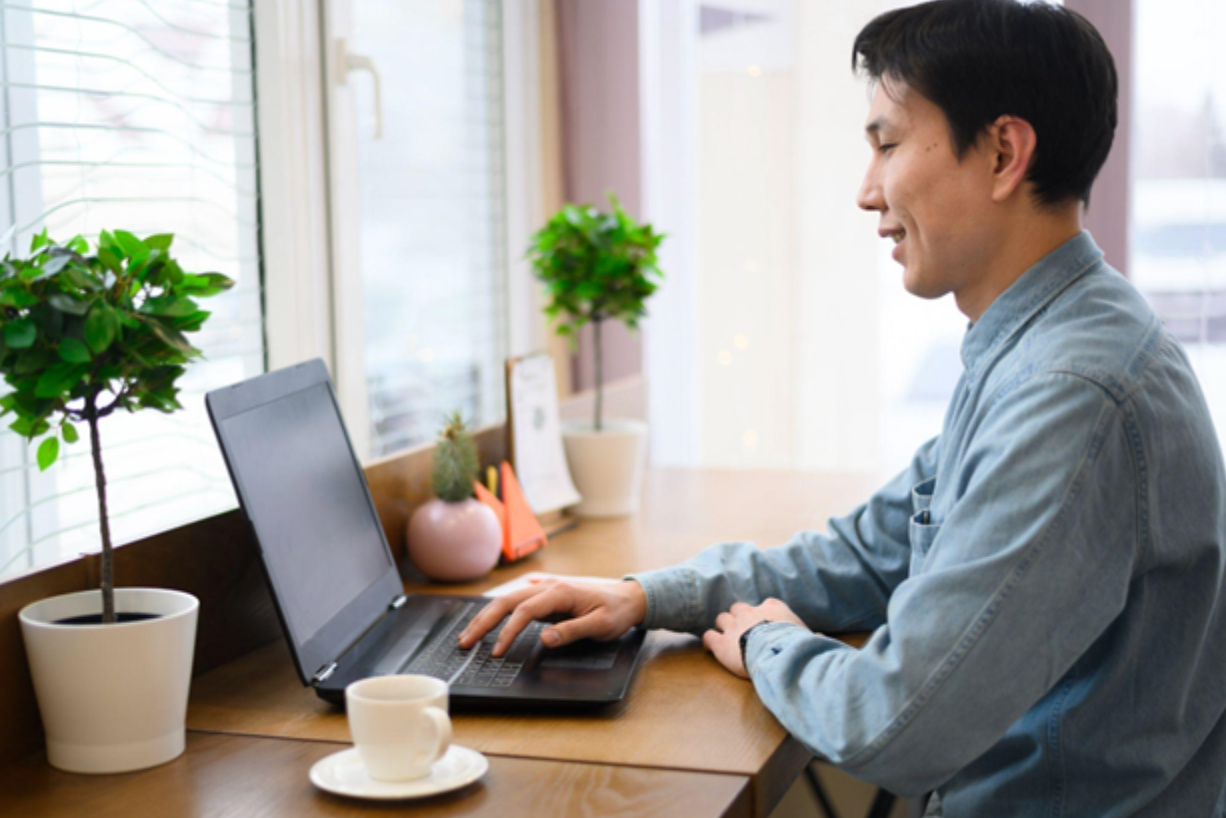 Asian man seated in front of a laptop