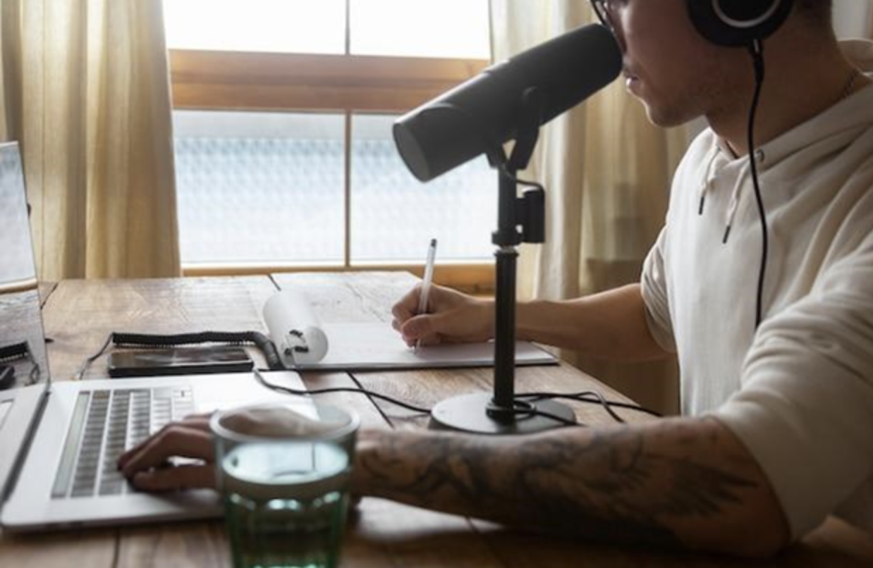 A job seeker preparing for a virtual interview by testing his microphone and taking down notes