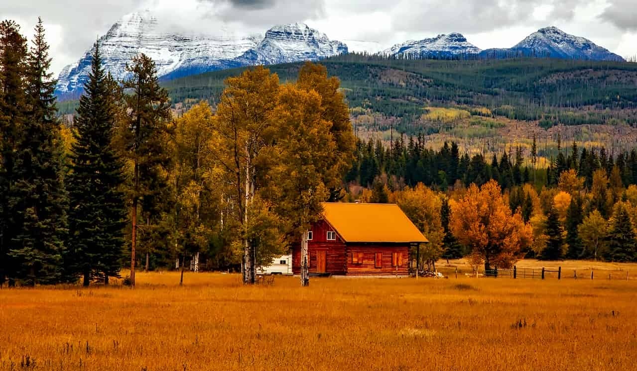 A cabin in a field with mountains in the background