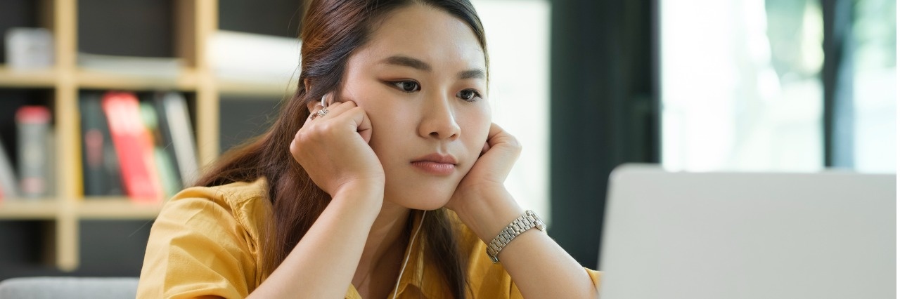 A woman in a yellow blouse looking at her computer