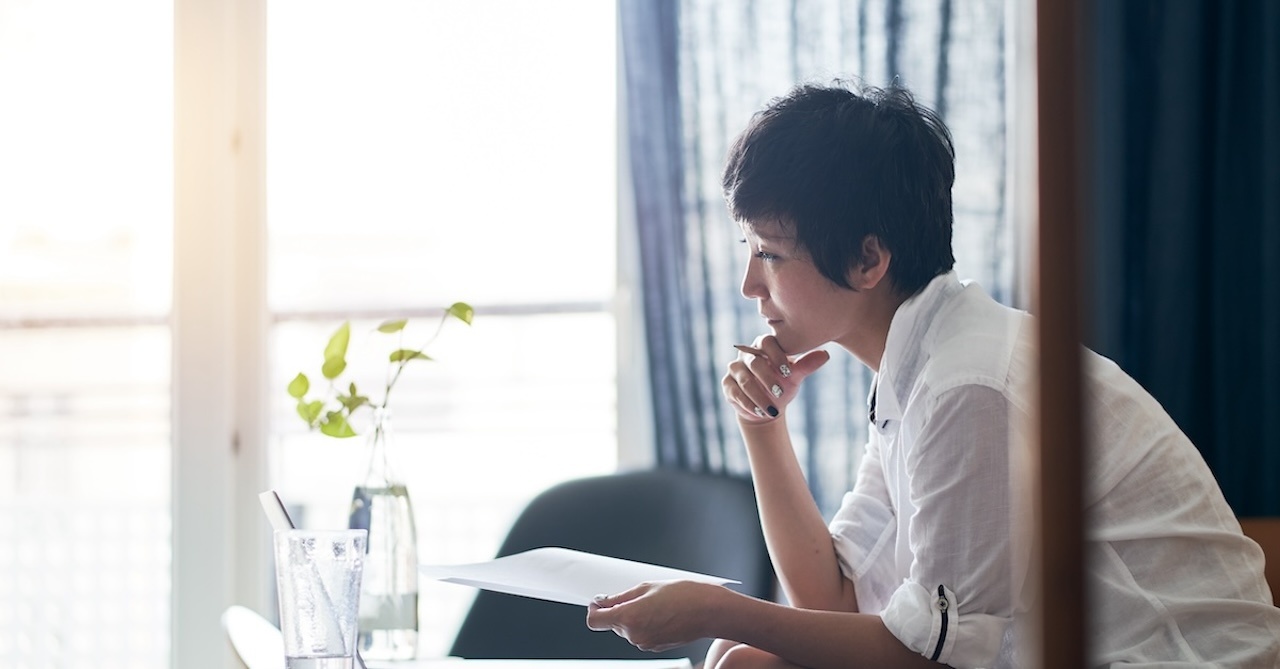 asian woman sitting and thinking with her resume in hand