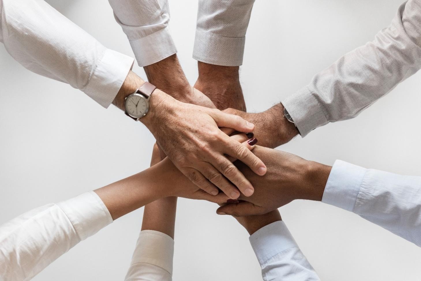 multiple people stacking their hands together in a gesture of teamwork and unity