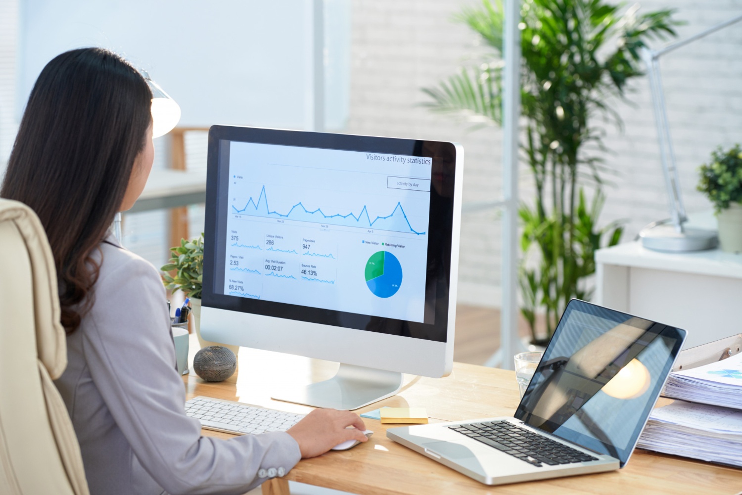 Seorang data analyst sedang bekerja menggunakan laptop dan komputer. (Image by pressfoto on Freepik)