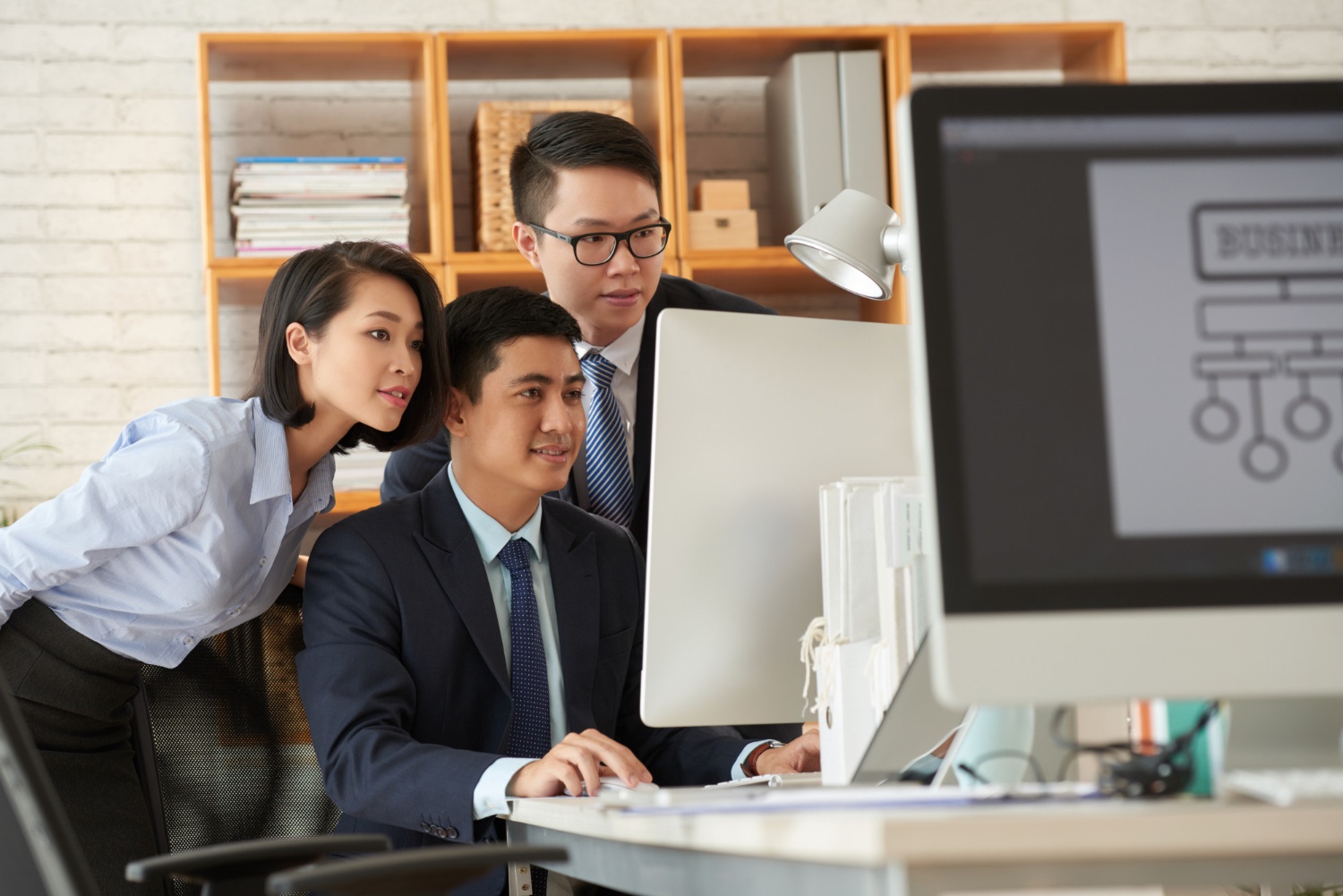 Tiga orang karyawan yang punya etos kerja tinggi sedang berdiskusi di kantor.