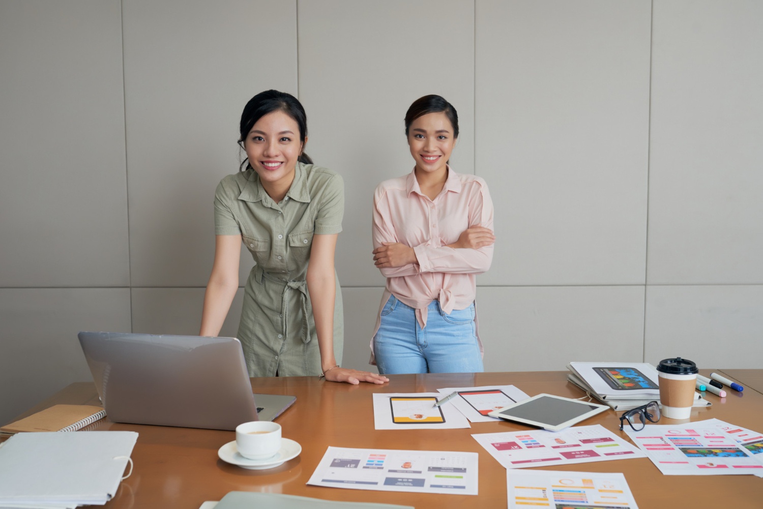 Dua orang wanita berdiri di depan meja sebagai tahapan dalam Pembuatan Minimum Viable Product