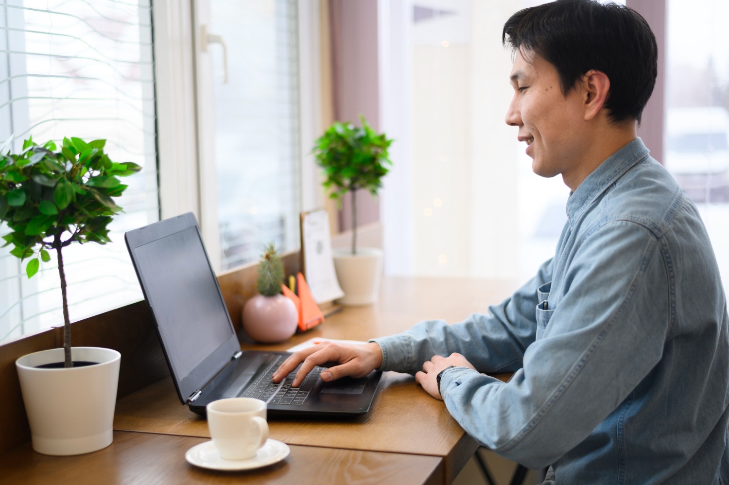 Asian man seated in front of a laptop