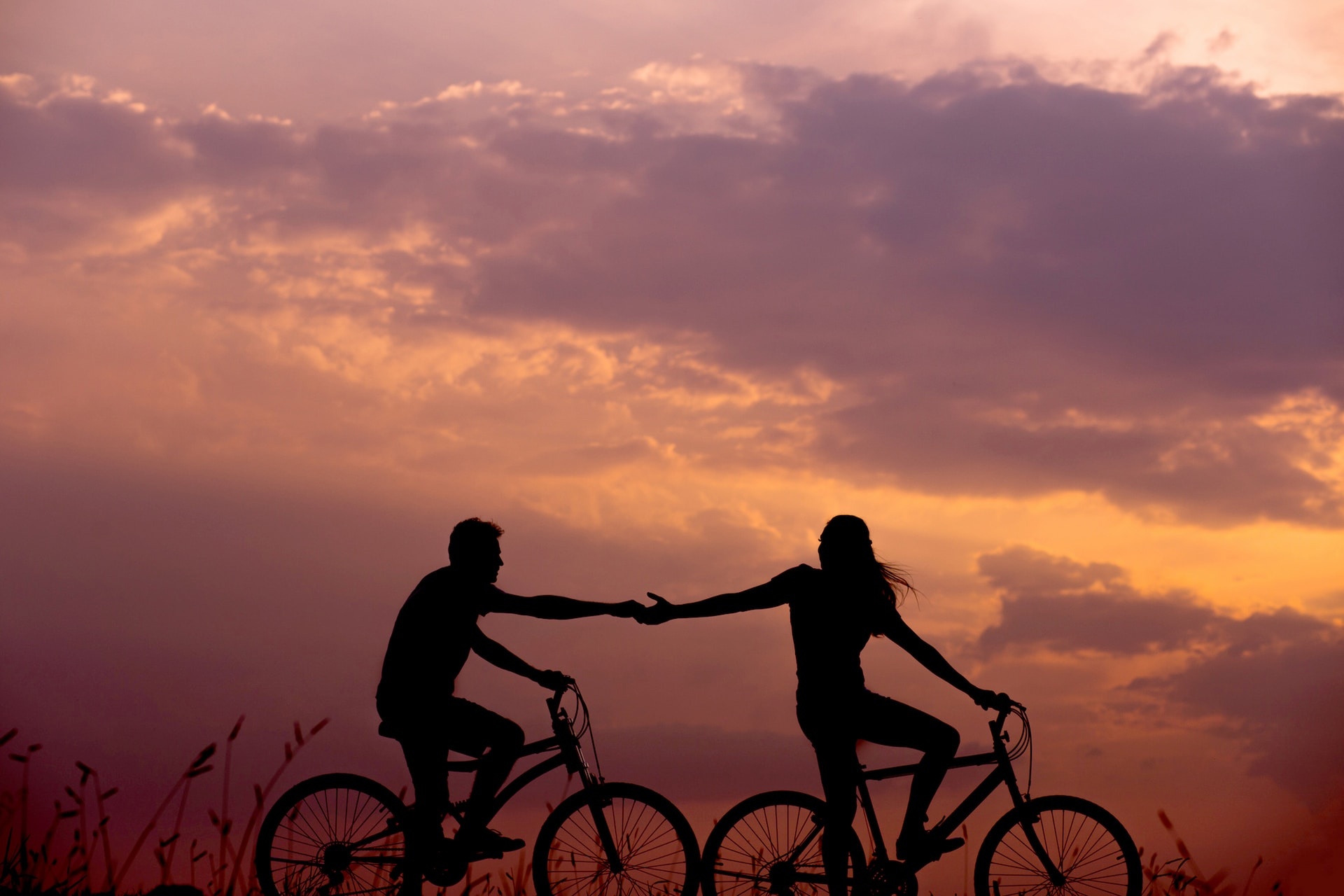 Man and woman riding their bicycles in the sunset