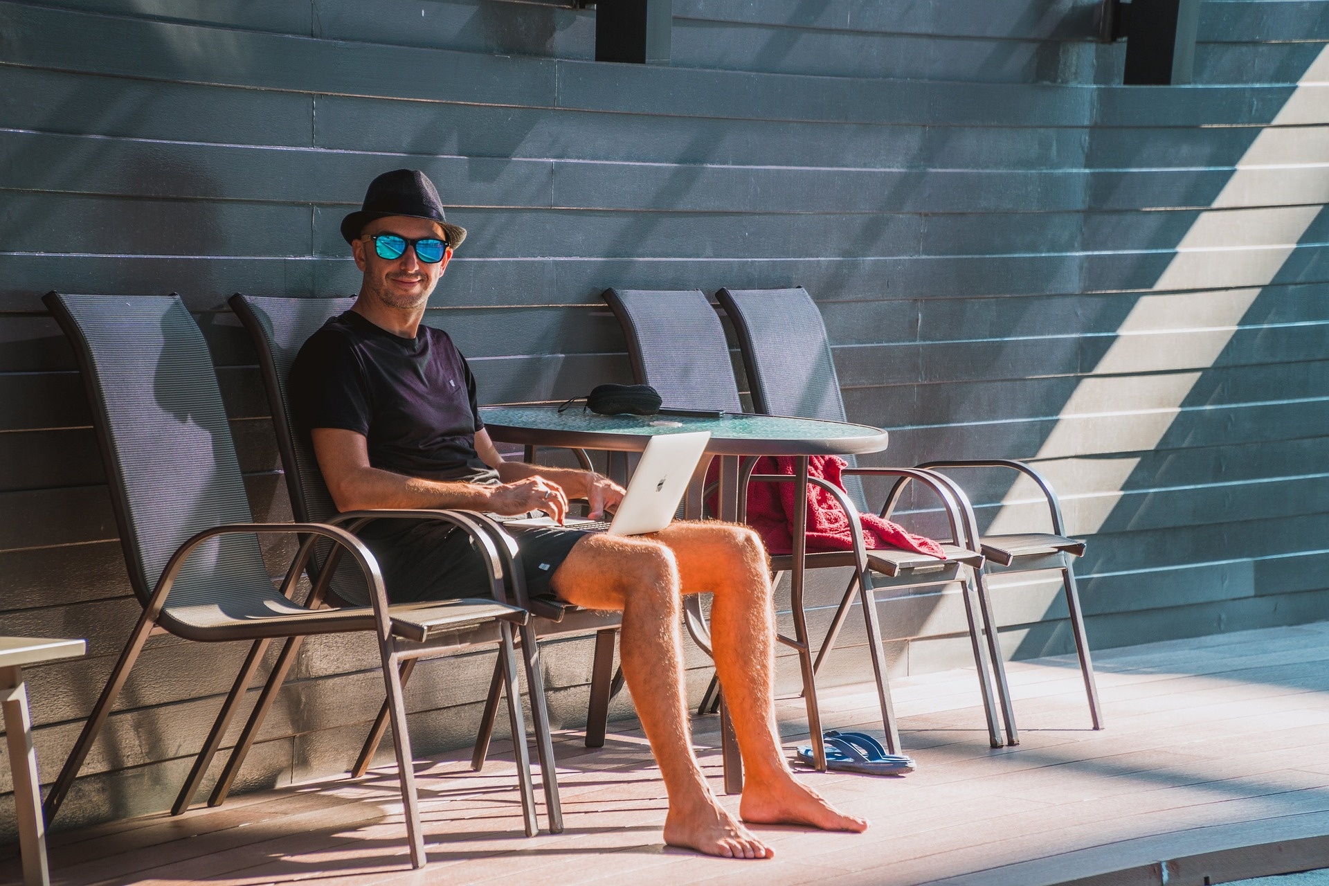 Man wearing sunglasses is working on his laptop while travelling