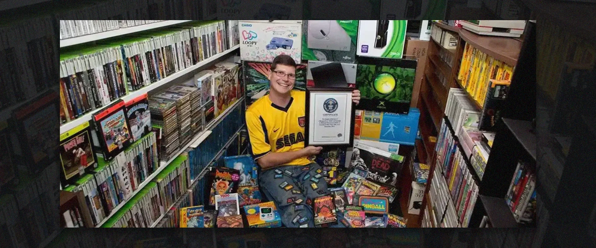 imagem de um homem no centro de uma coleção de diversos jogos de videogame com um certificado na suas mãos