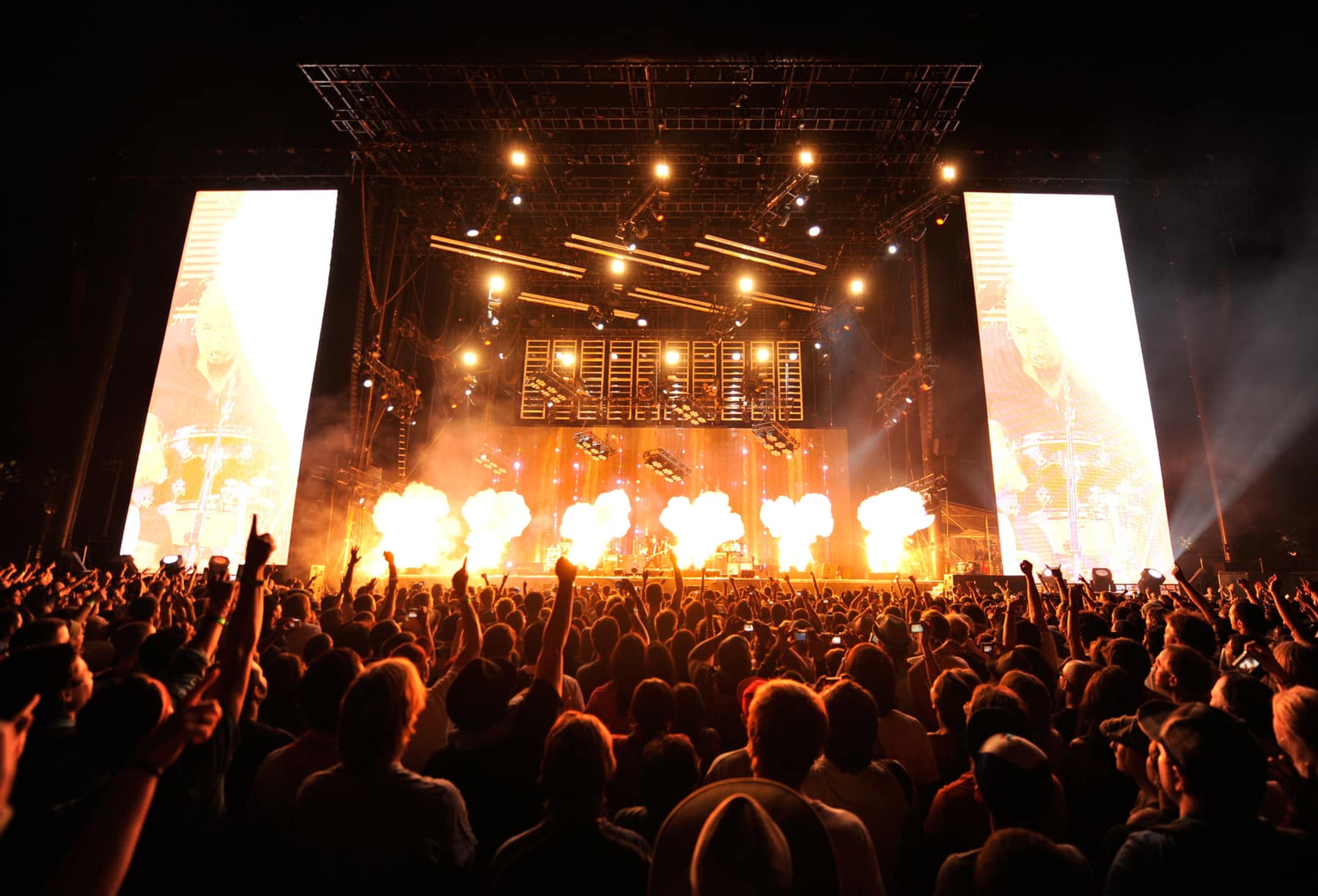 A crowd of people watching pyrotechnics on stage
