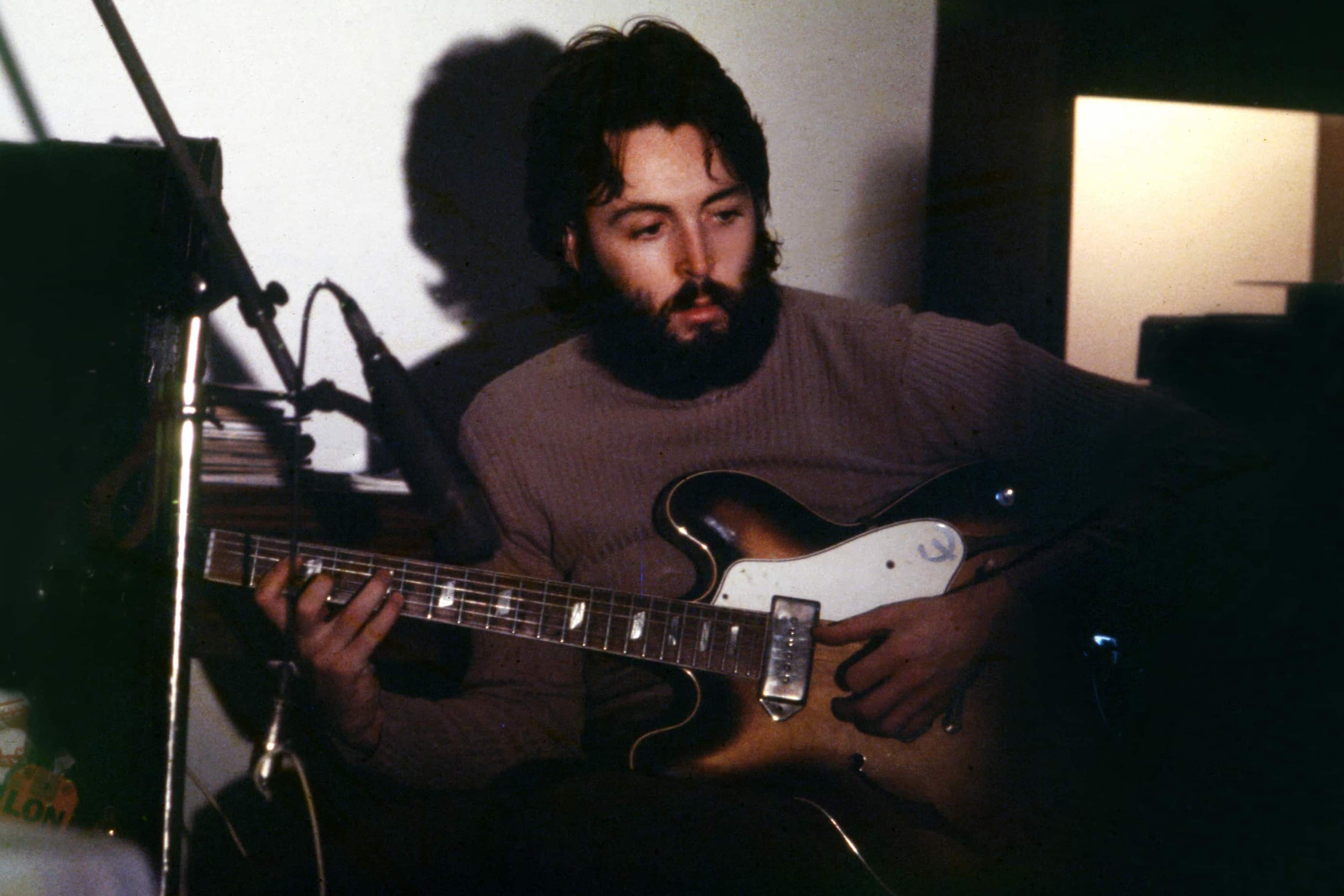 Landscape colour photo of Paul playing guitar in his home studio recording 'McCartney'