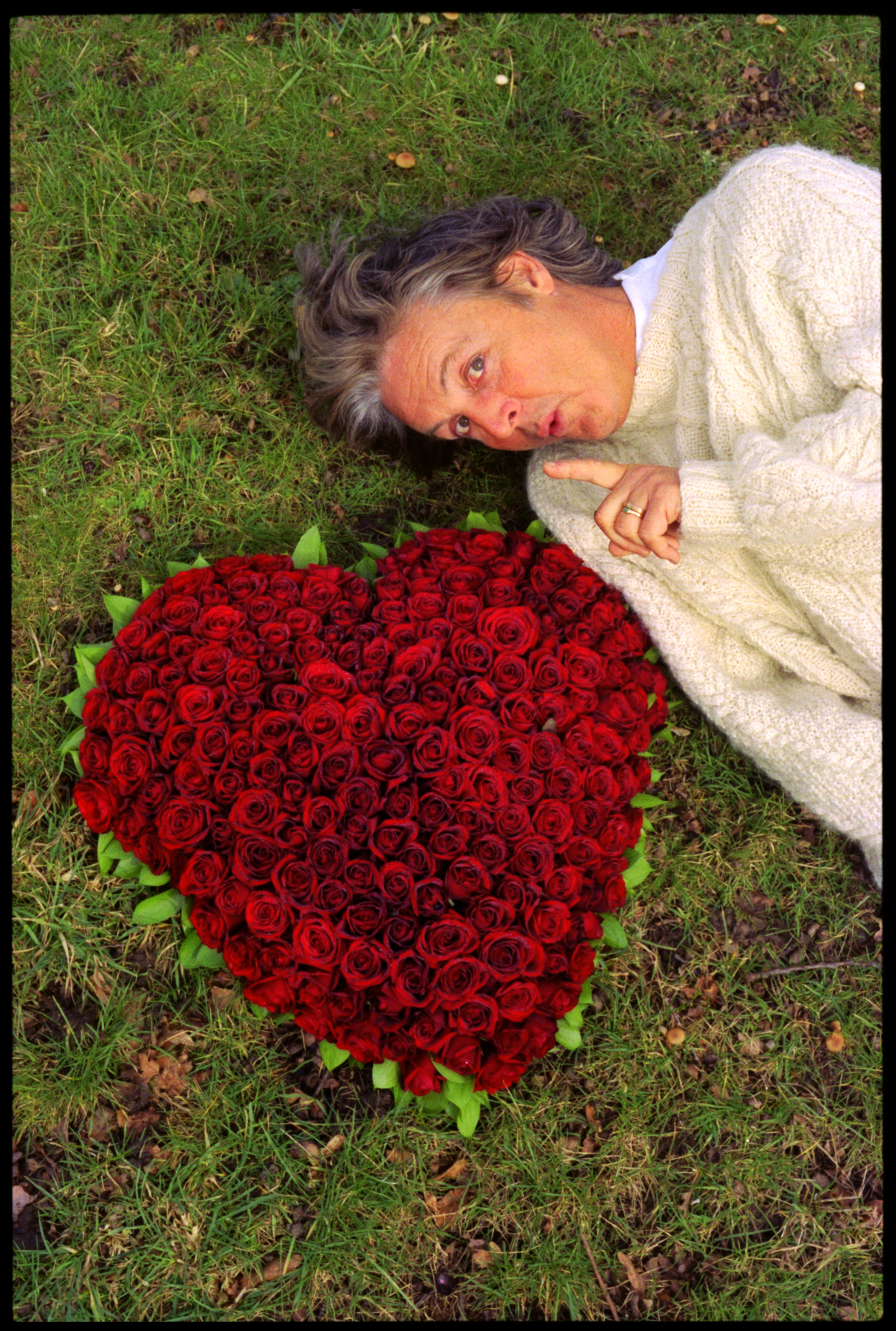Paul lying on the ground with a heart-shaped display of red roses