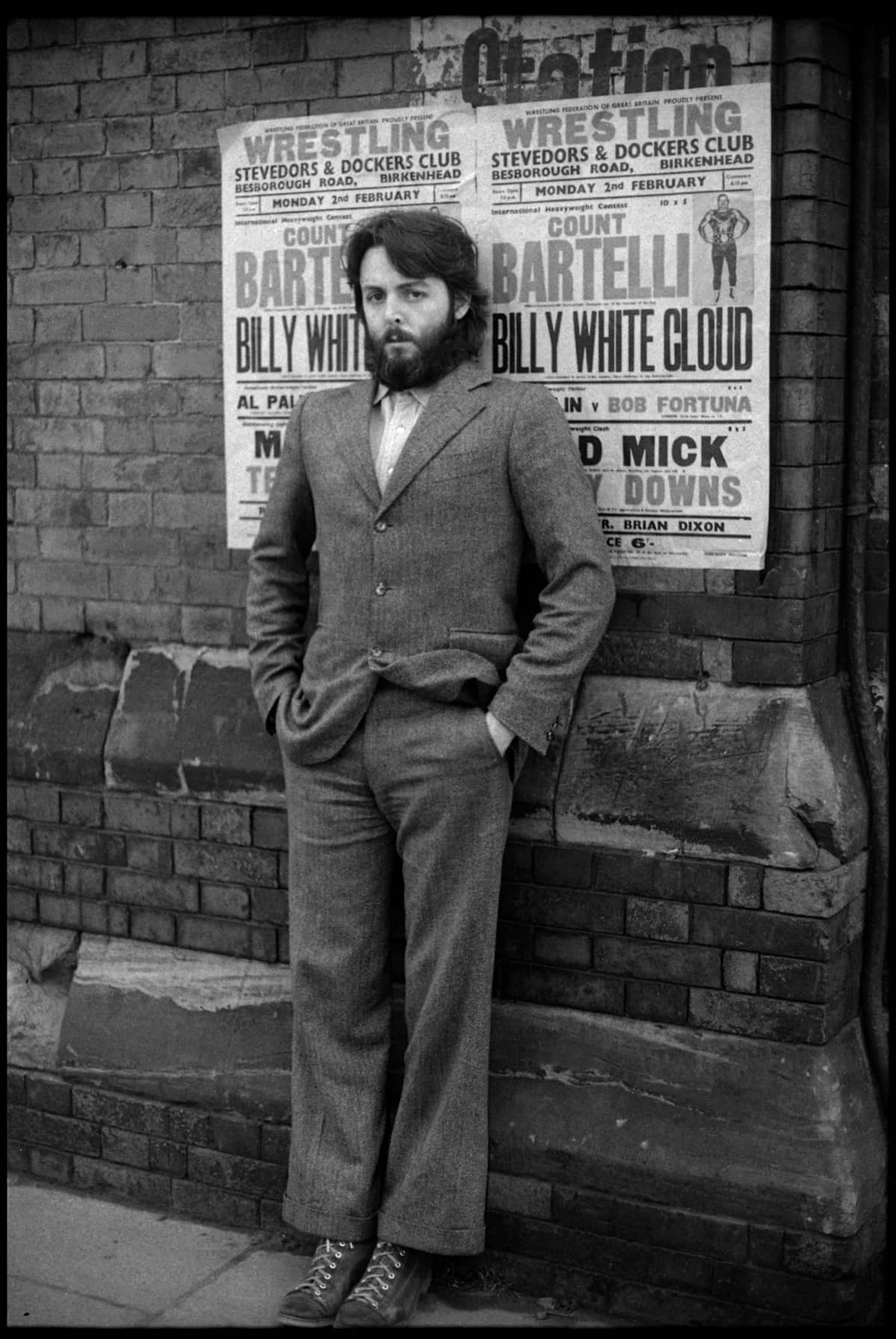 Black and white photo of Paul McCartney leaning against a wall