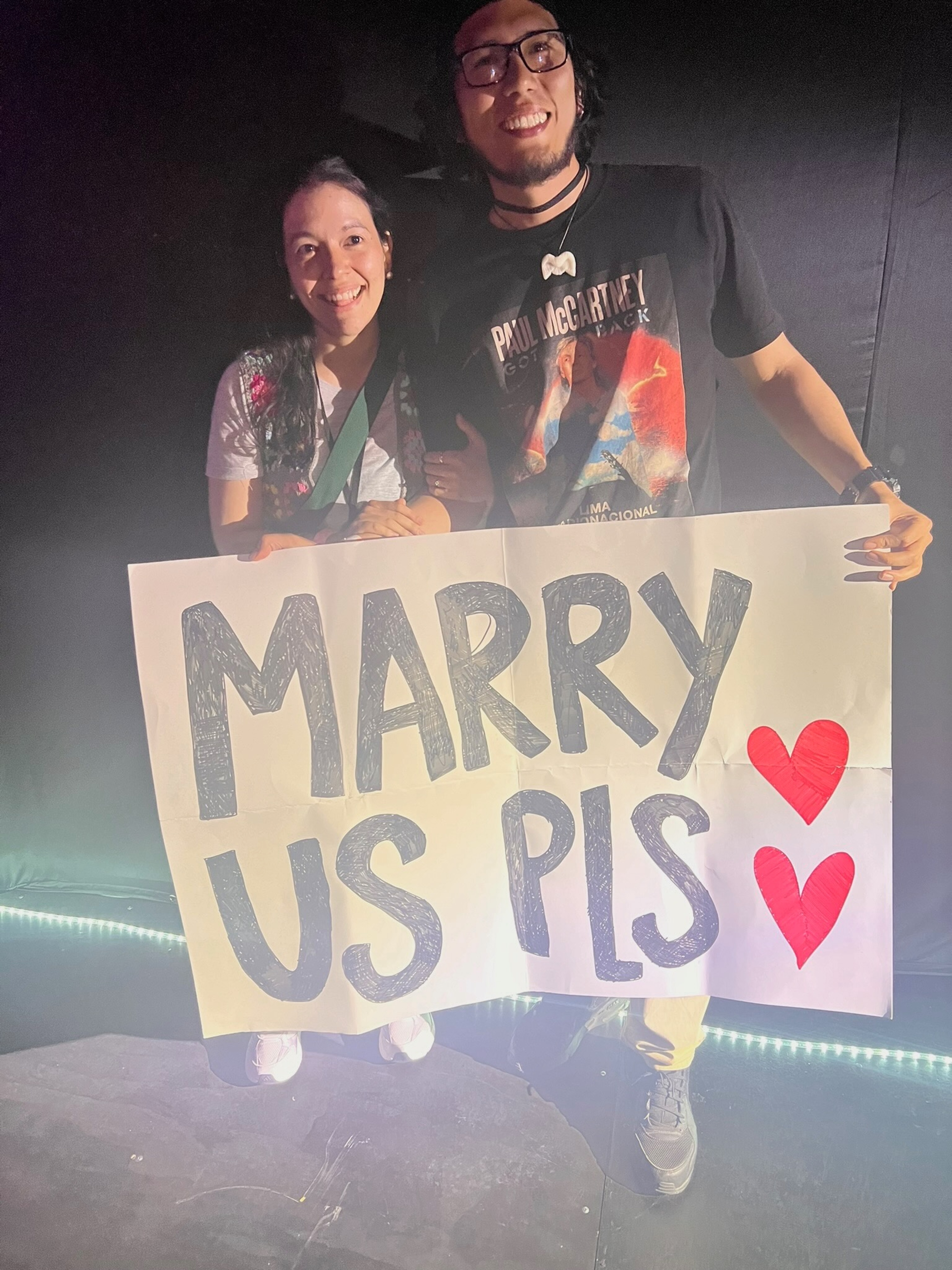 Aixa Salinas and her fiancé Jazet holding their "Marry Us Pls" sign.