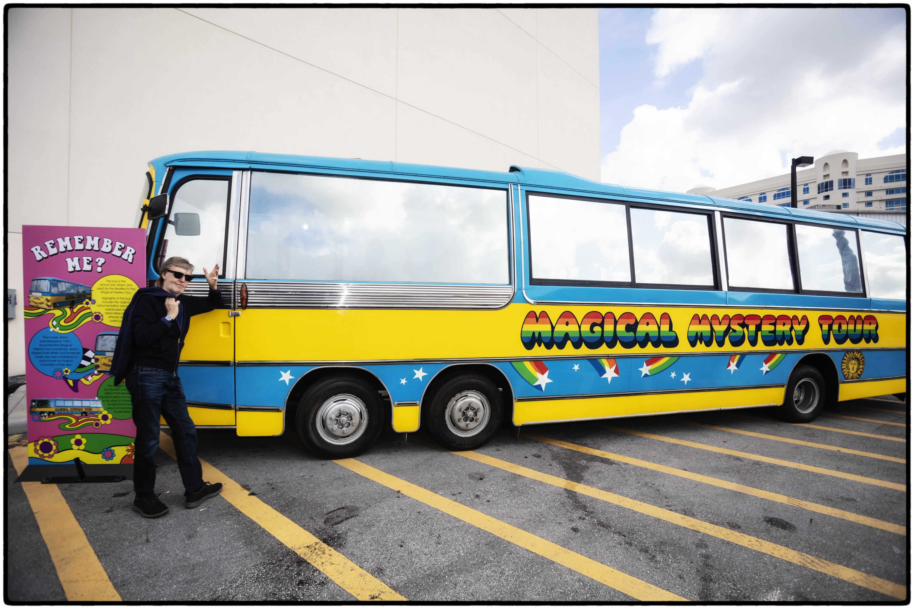 Paul stands in front of the Magical Mystery Tour bus