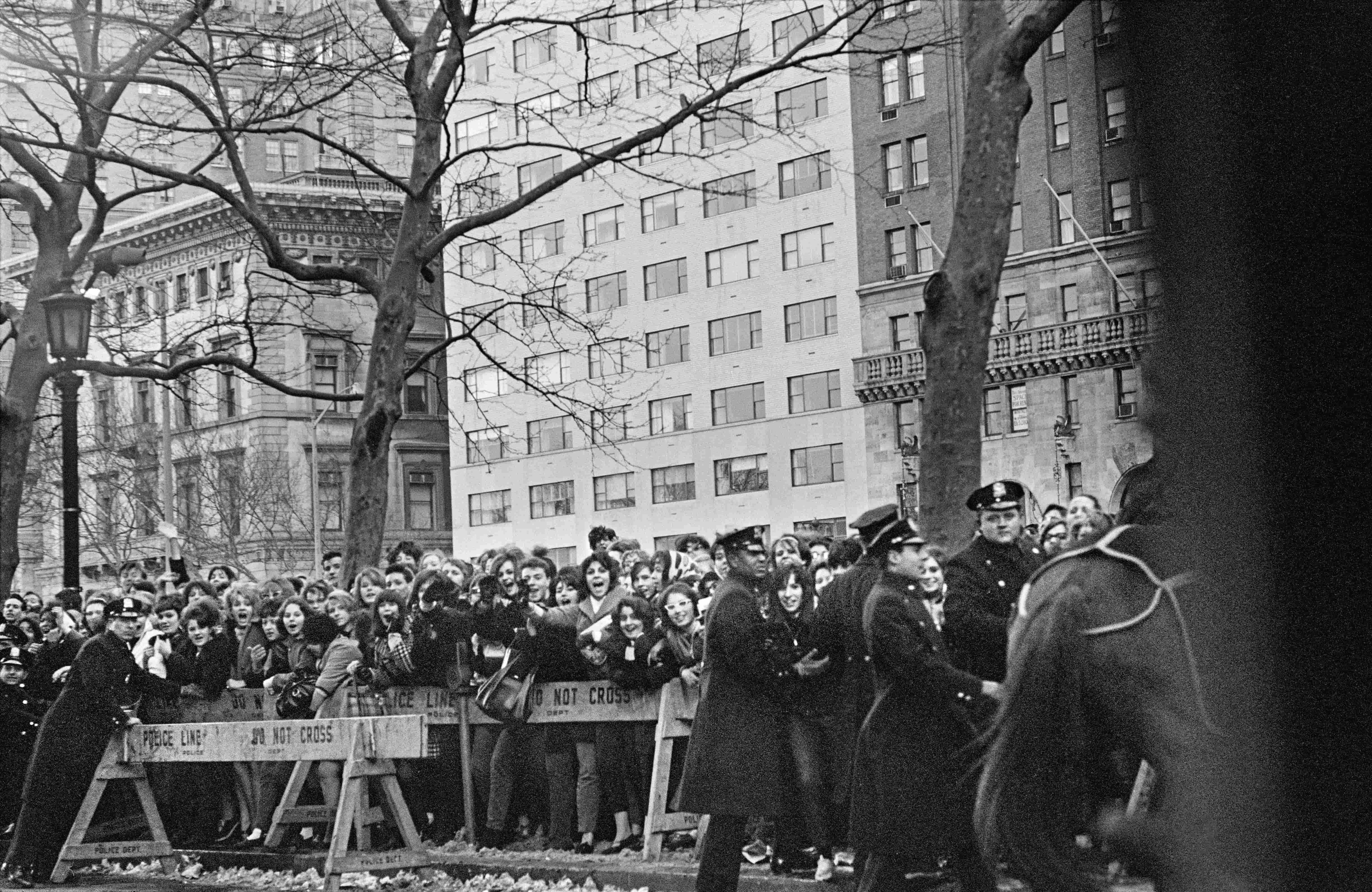 Black and white photo of a crowd of fans behind a barricade in New York's Central Park