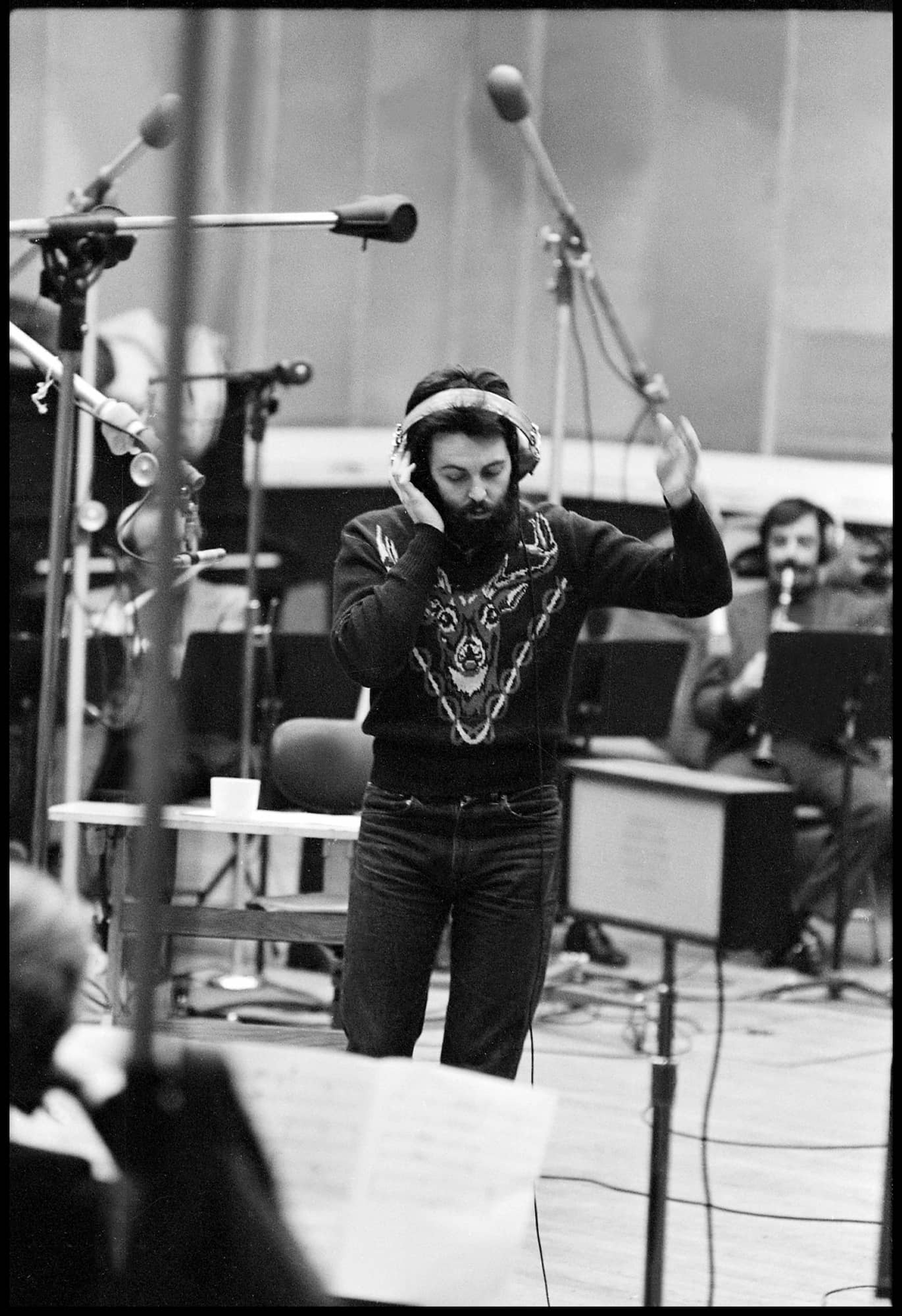 Black and white photo of Paul in the studio conducting musicians