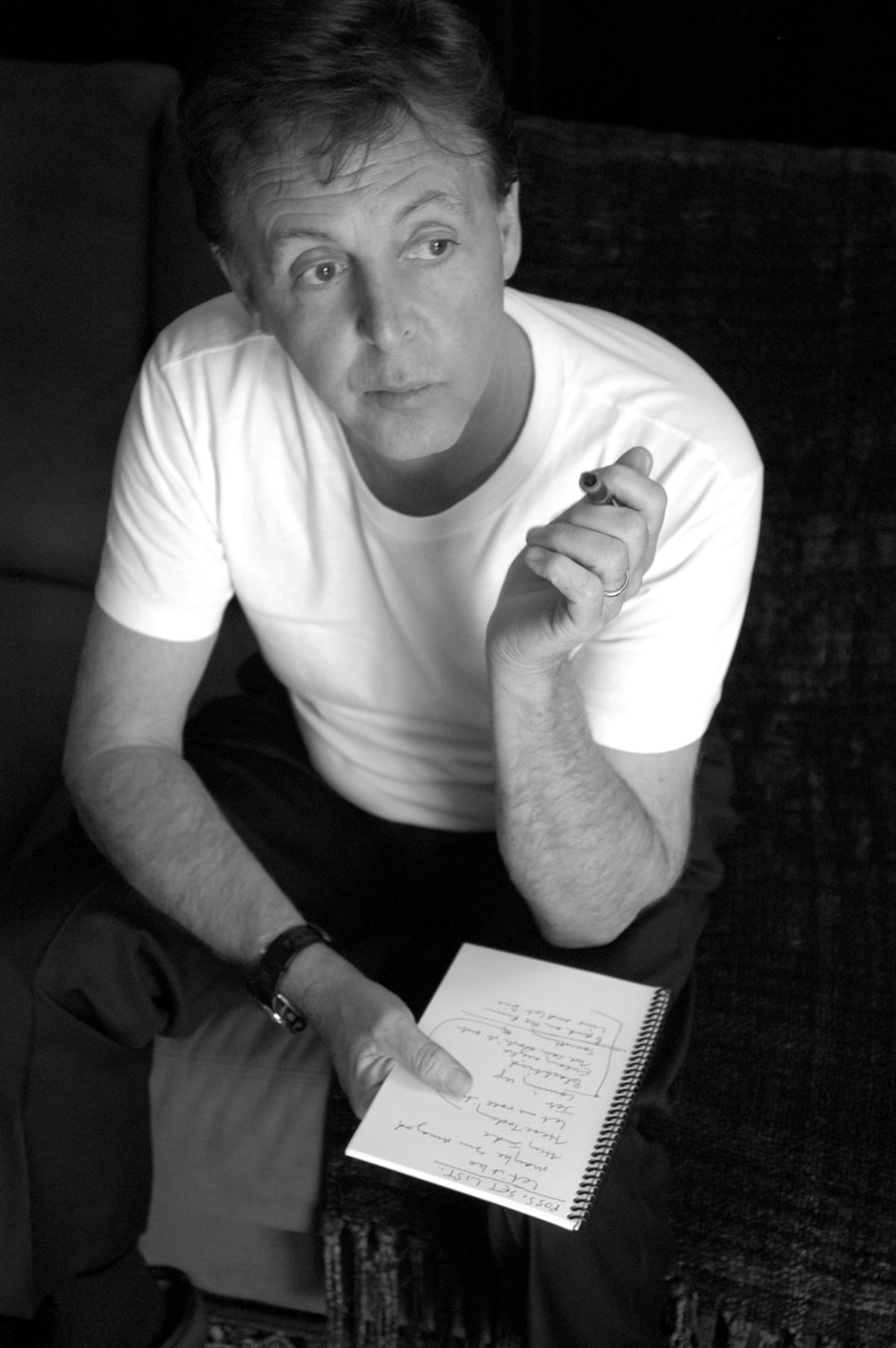 Back and white photo of Paul McCartney backstage in Dublin, holding a pen and paper.