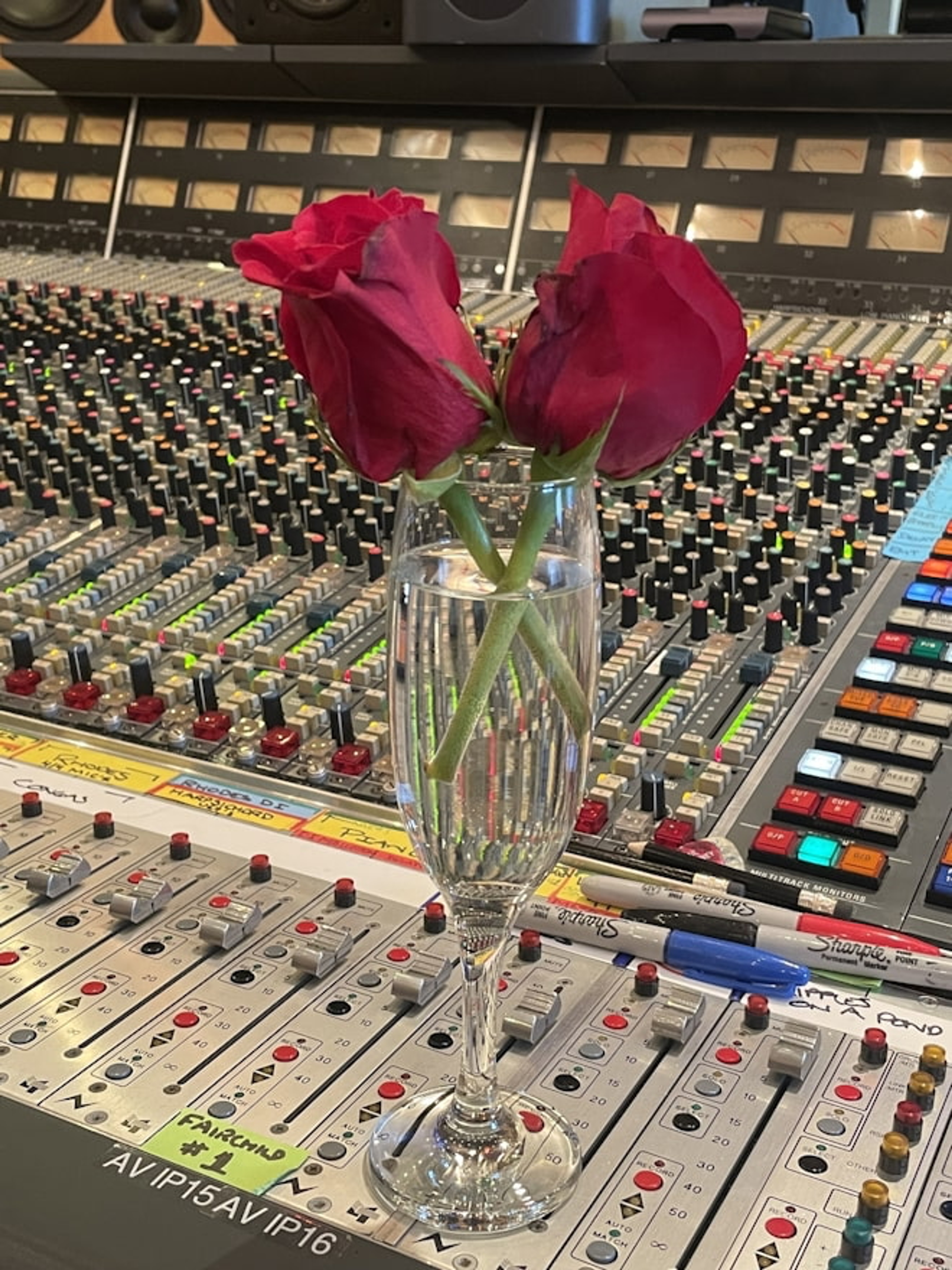iPhone photograph of two roses in a wine glass on a music studio mixing board