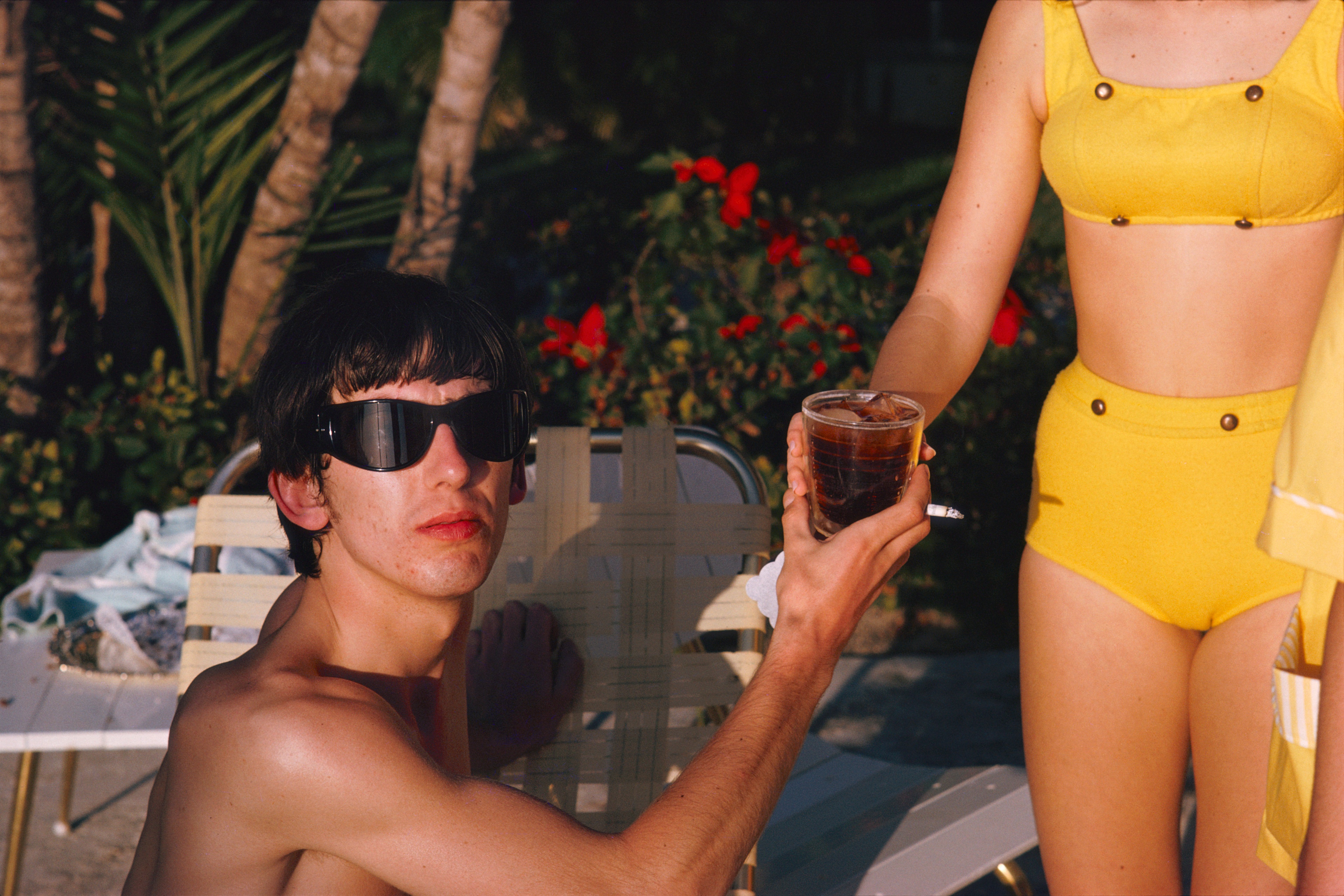 Colour photograph of George Harrison in Miami being handed a drink by a bikini clad women