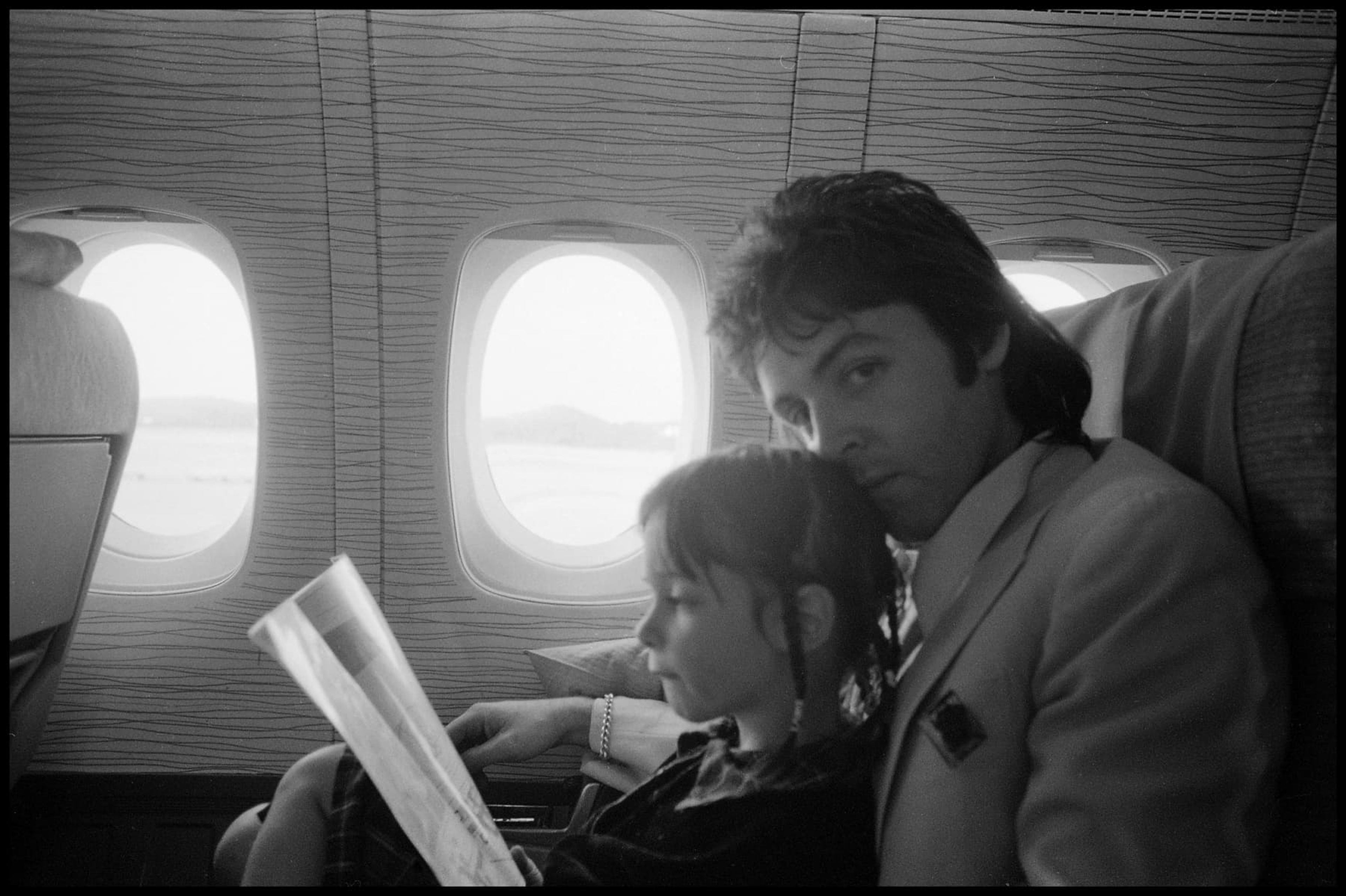 Young Mary McCartney sits on Paul's lap on an aiplane