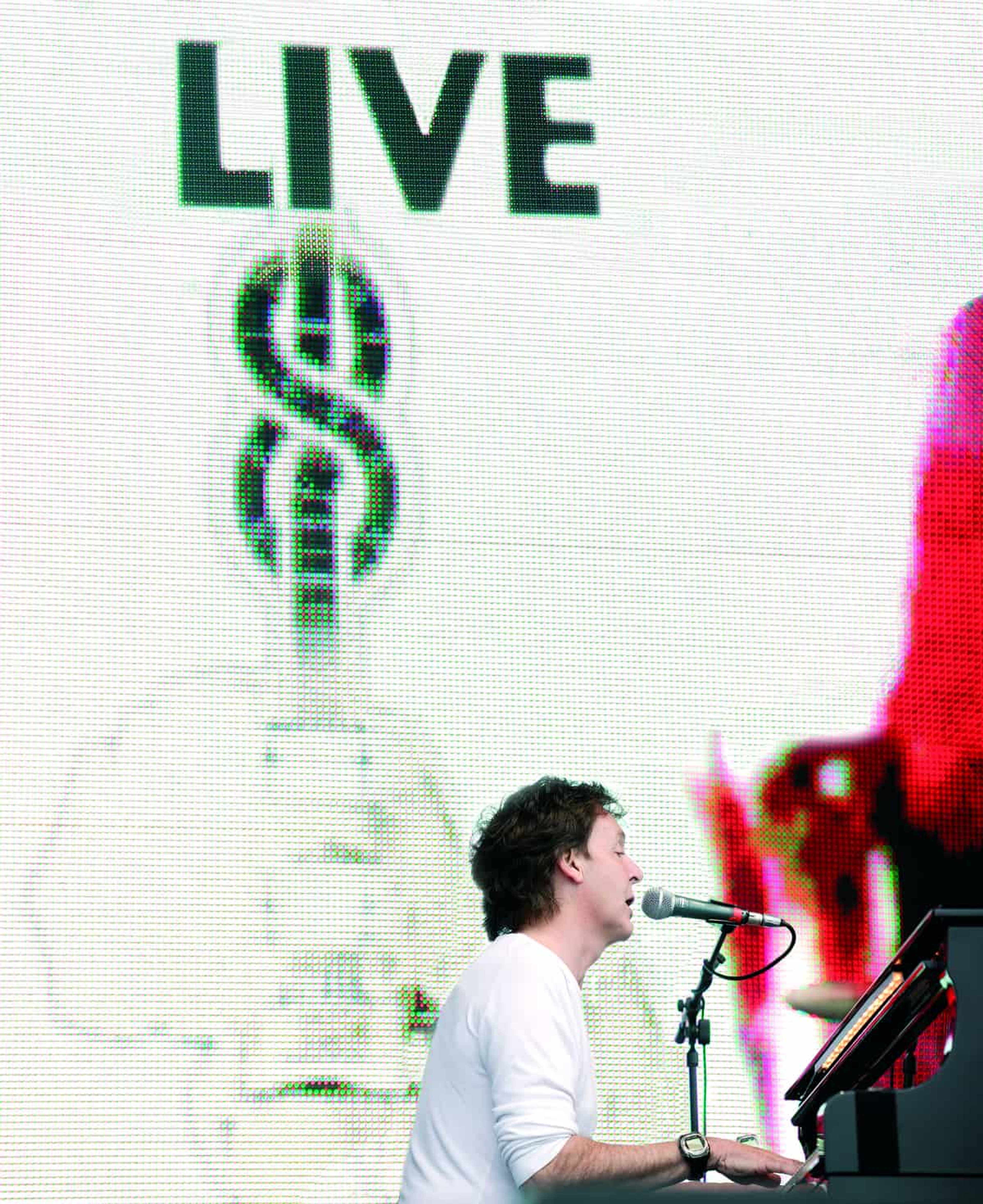 Paul sat at a piano in front of the Live 8 banner