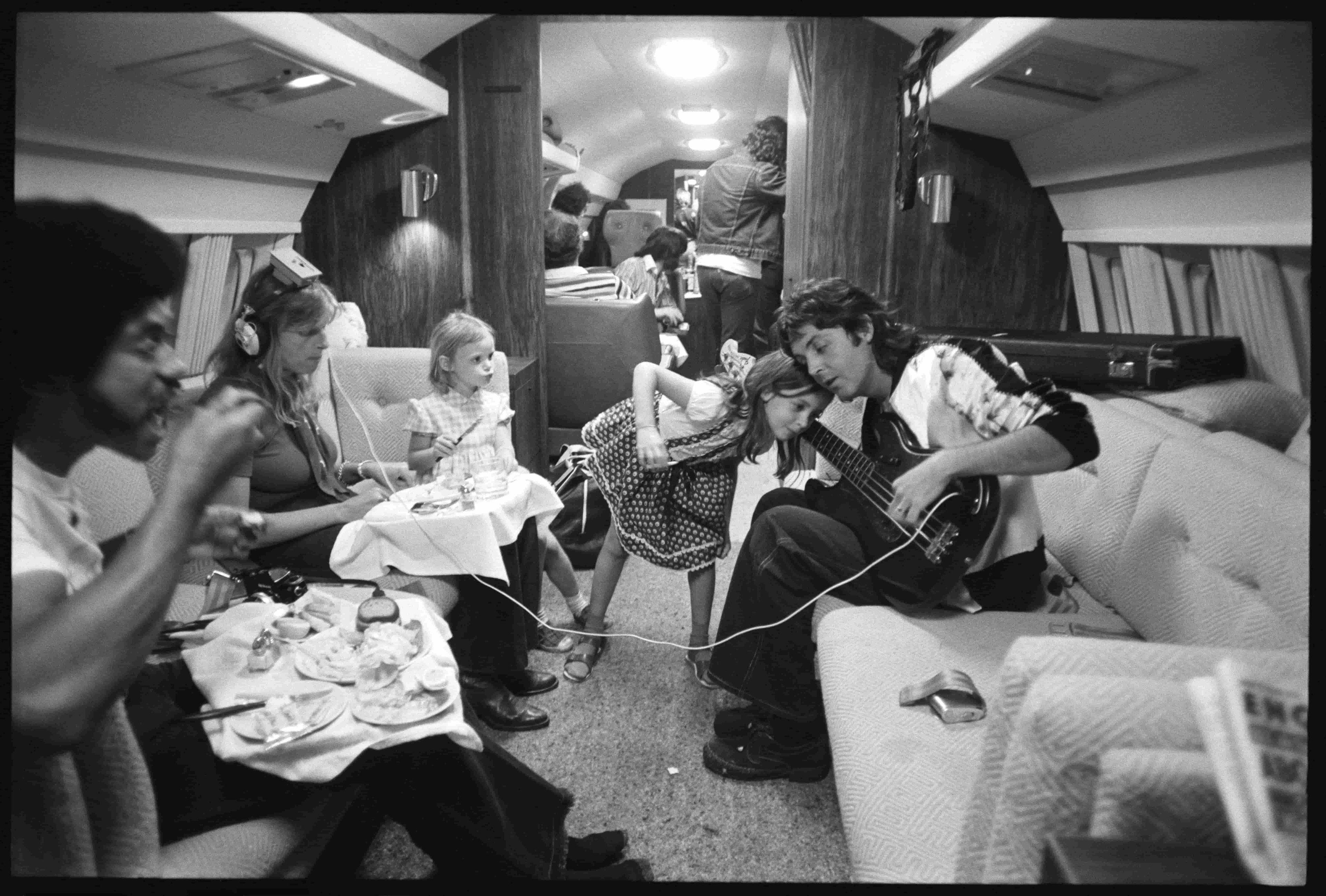 Wings band members and McCartney children play music on an airplane