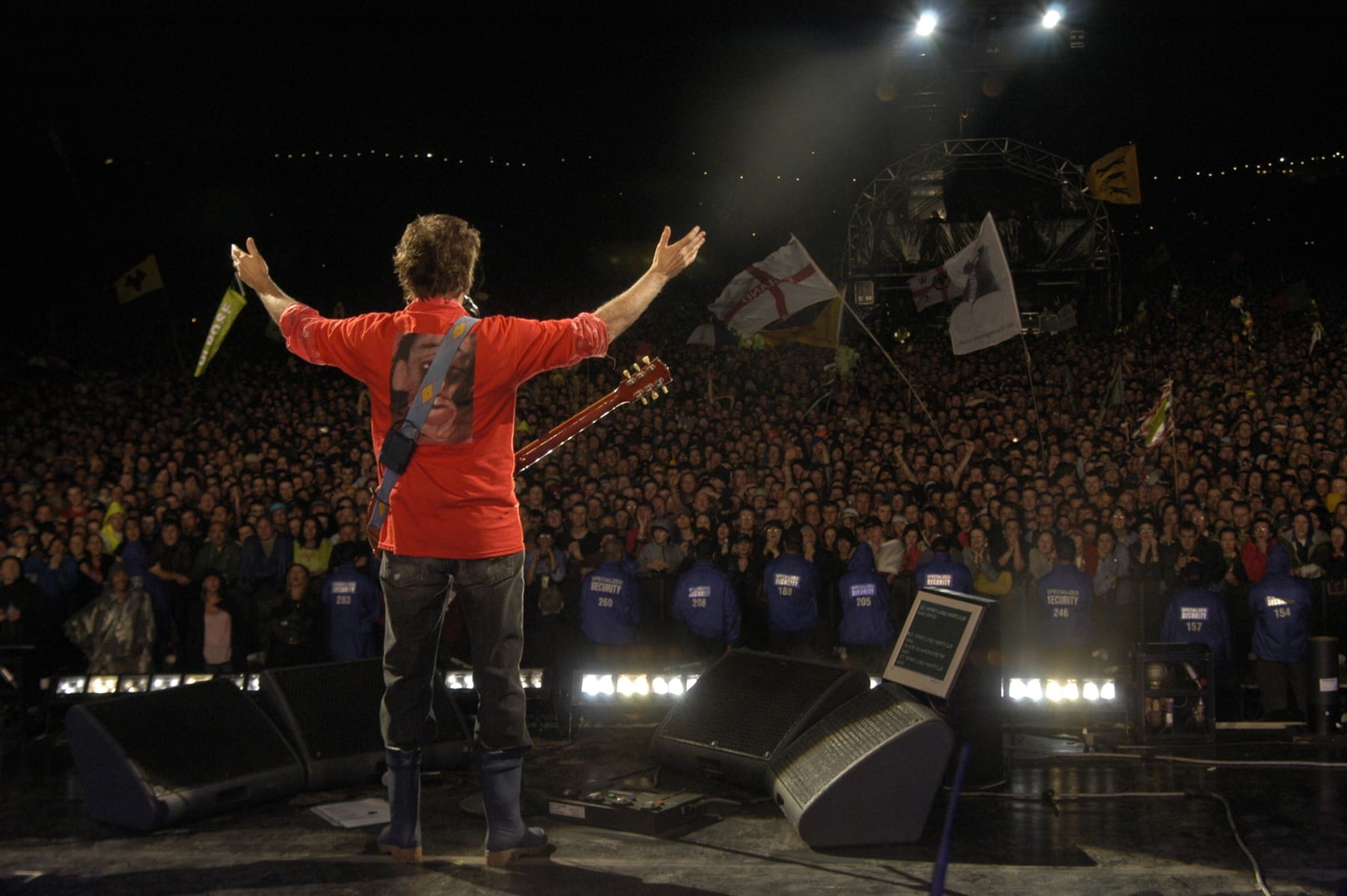 Paul standing in front of a crowd with his arms outstretched