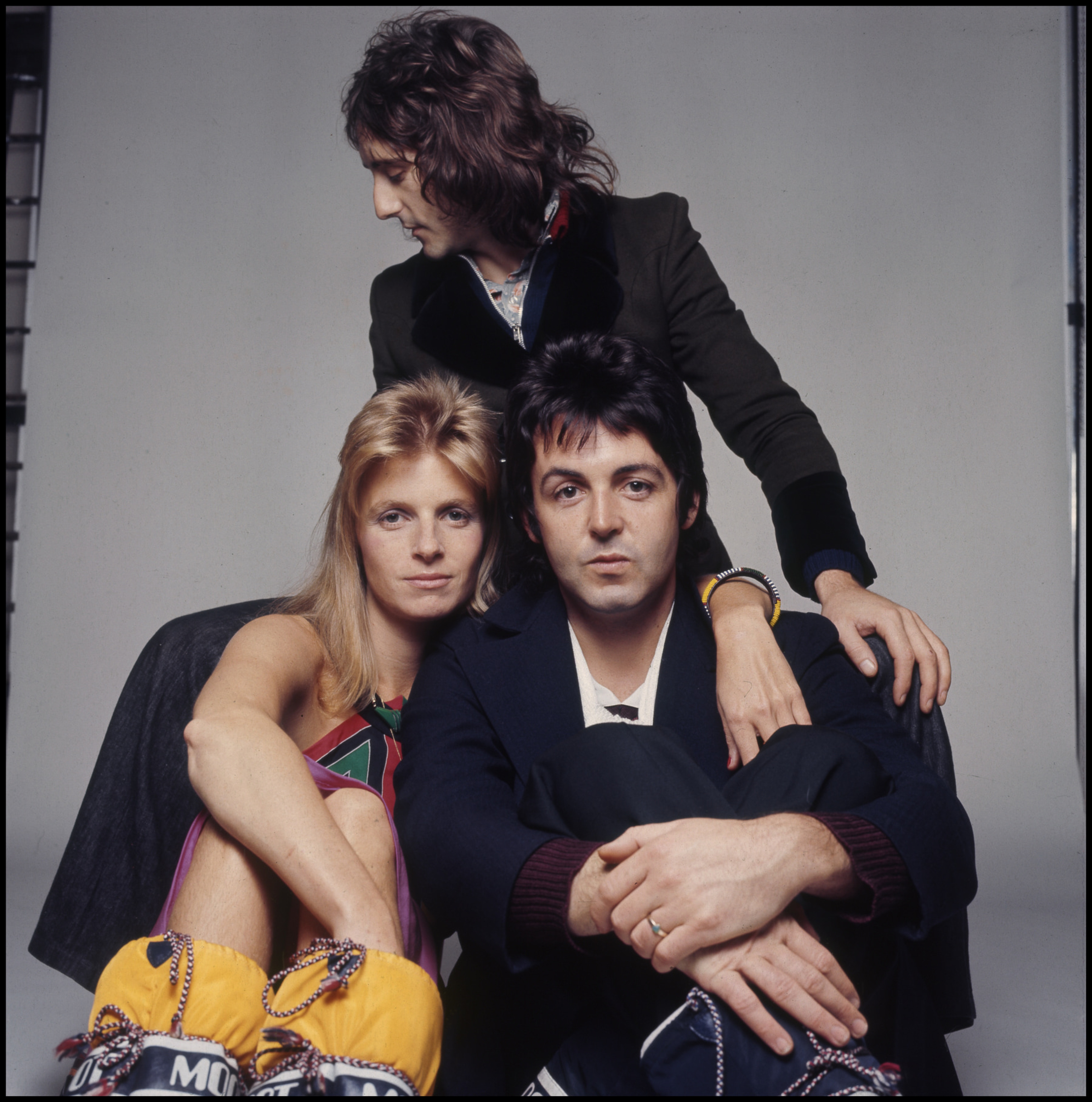 Denny Laine, Paul and Linda sitting down in front of a grey background