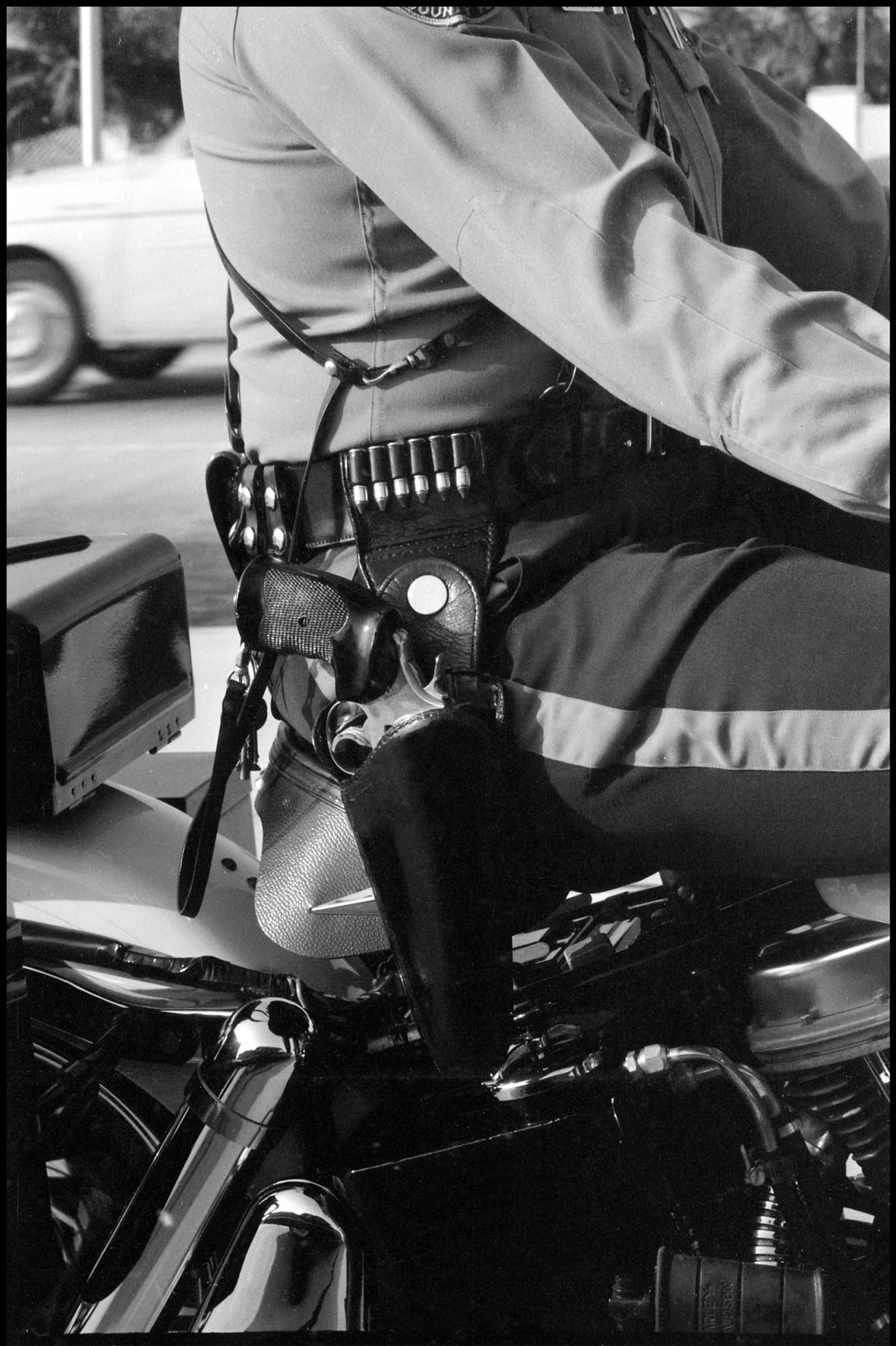 Black and white photo showing a gun on a policeman's belt